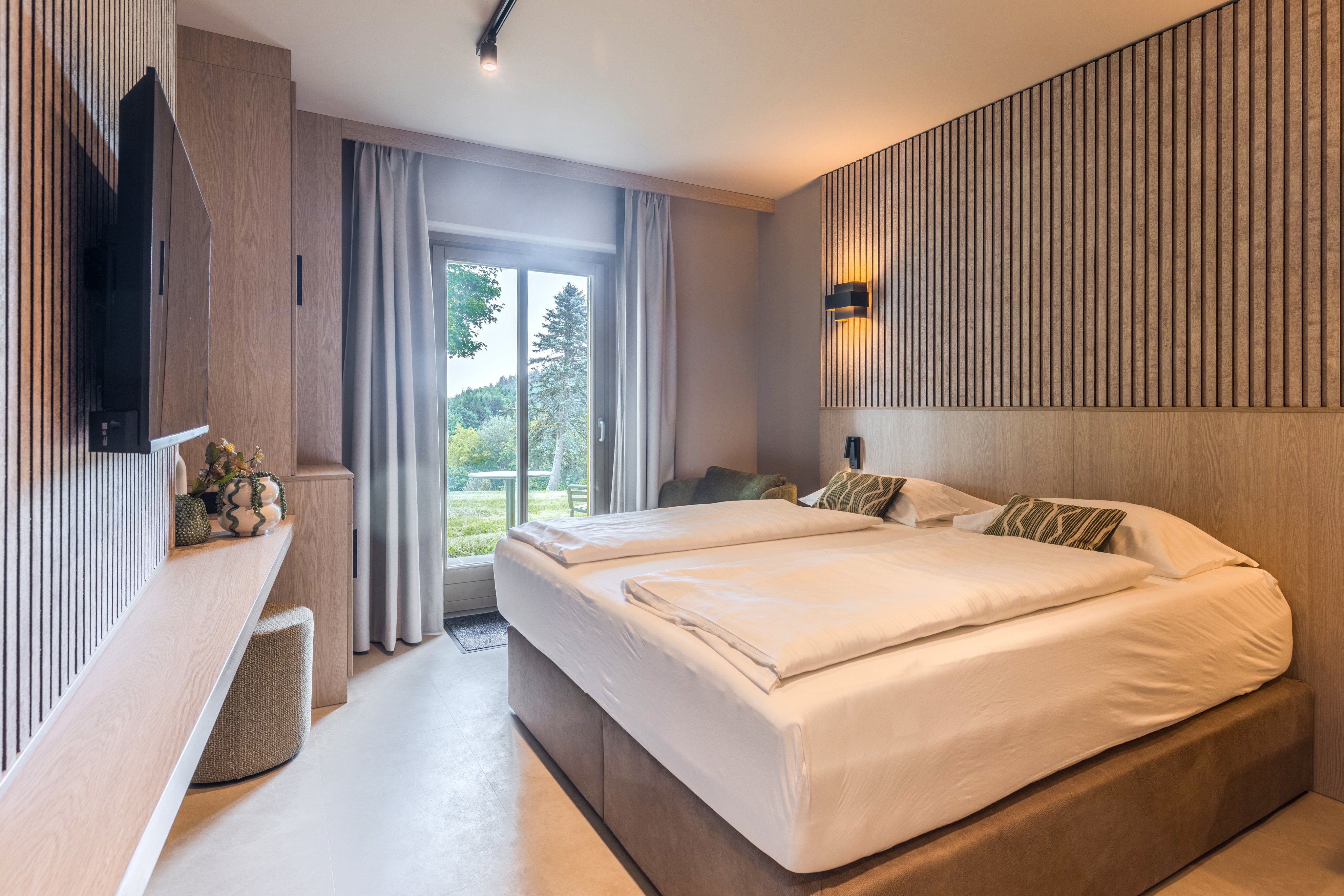 Schlafzimmer mit Doppelbett, Holzvertäfelung, Fenster mit Ausblick auf Natur, elegantes Design