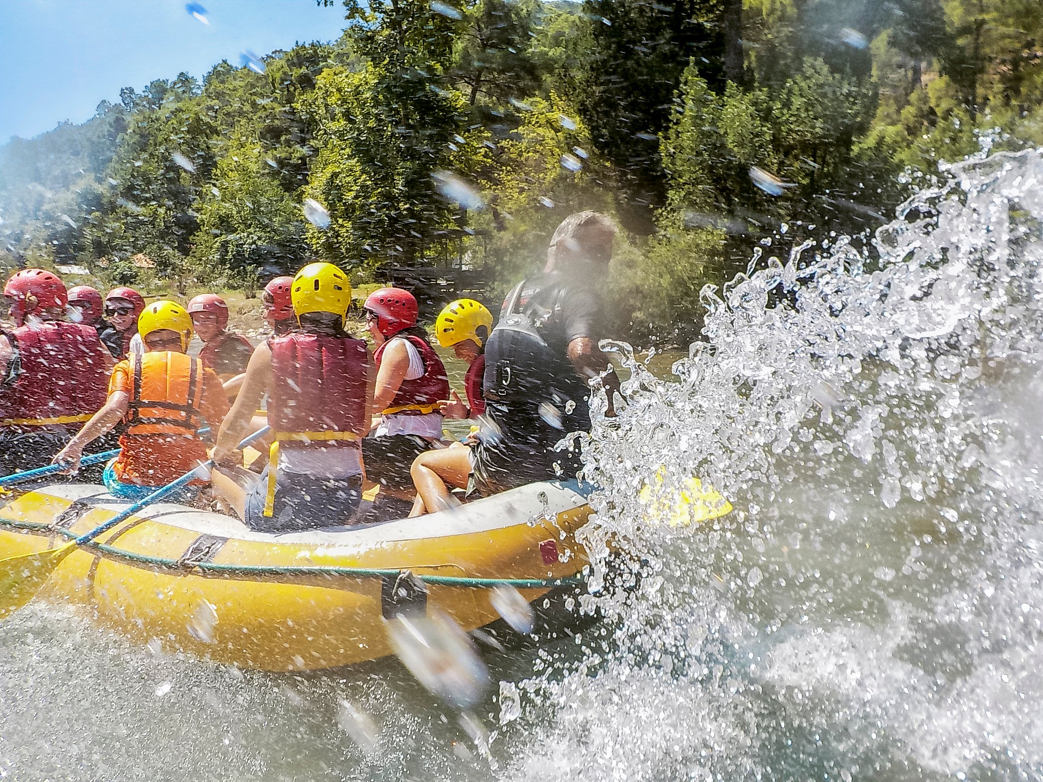 Menschen beim Wildwasser-Rafting auf einem Fluss in einer natürlichen Umgebung, Schutzhelme tragen