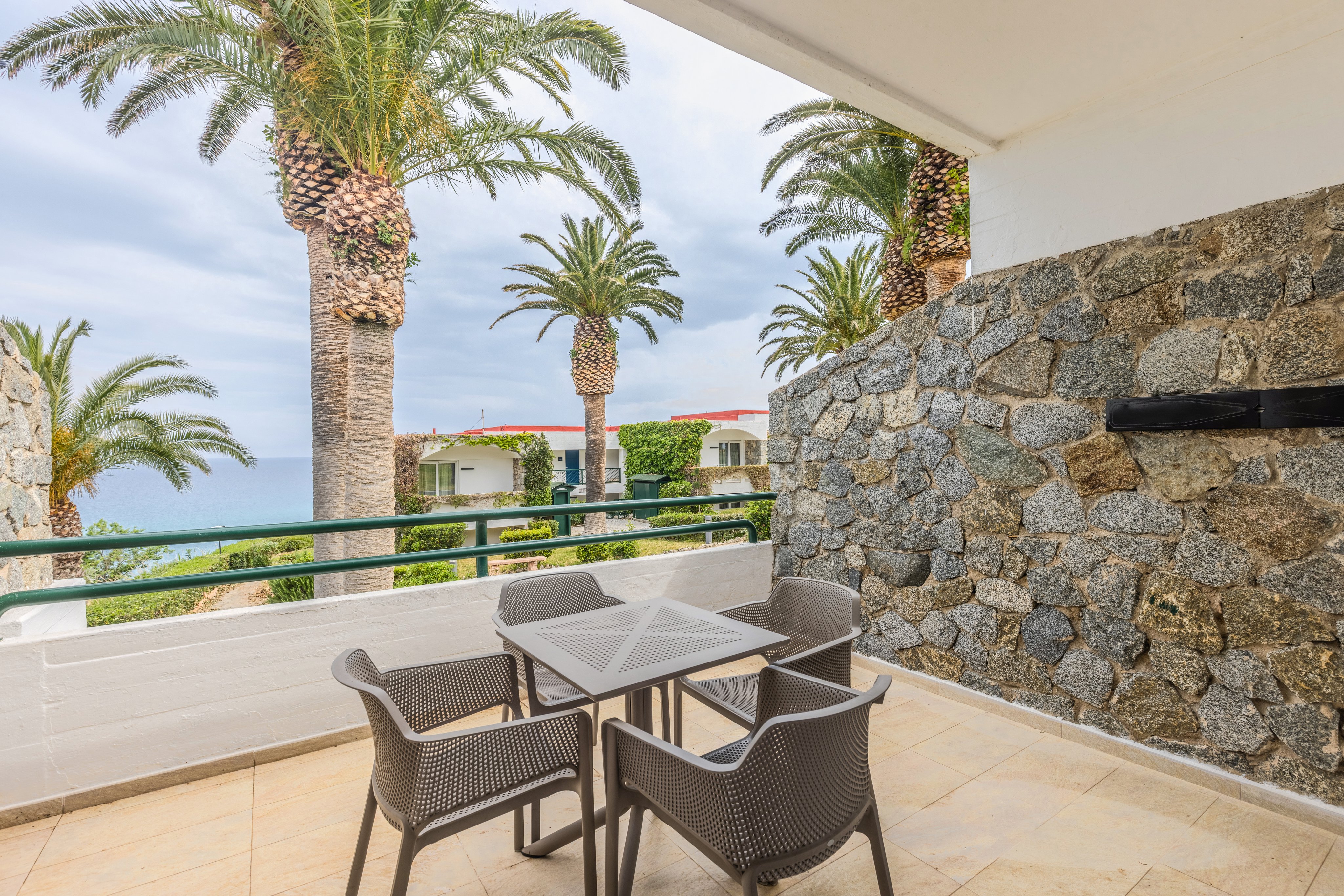 Eine Terrasse mit Blick auf Palmen und Meeresblick bei Aldiana, Premium Cluburlaub