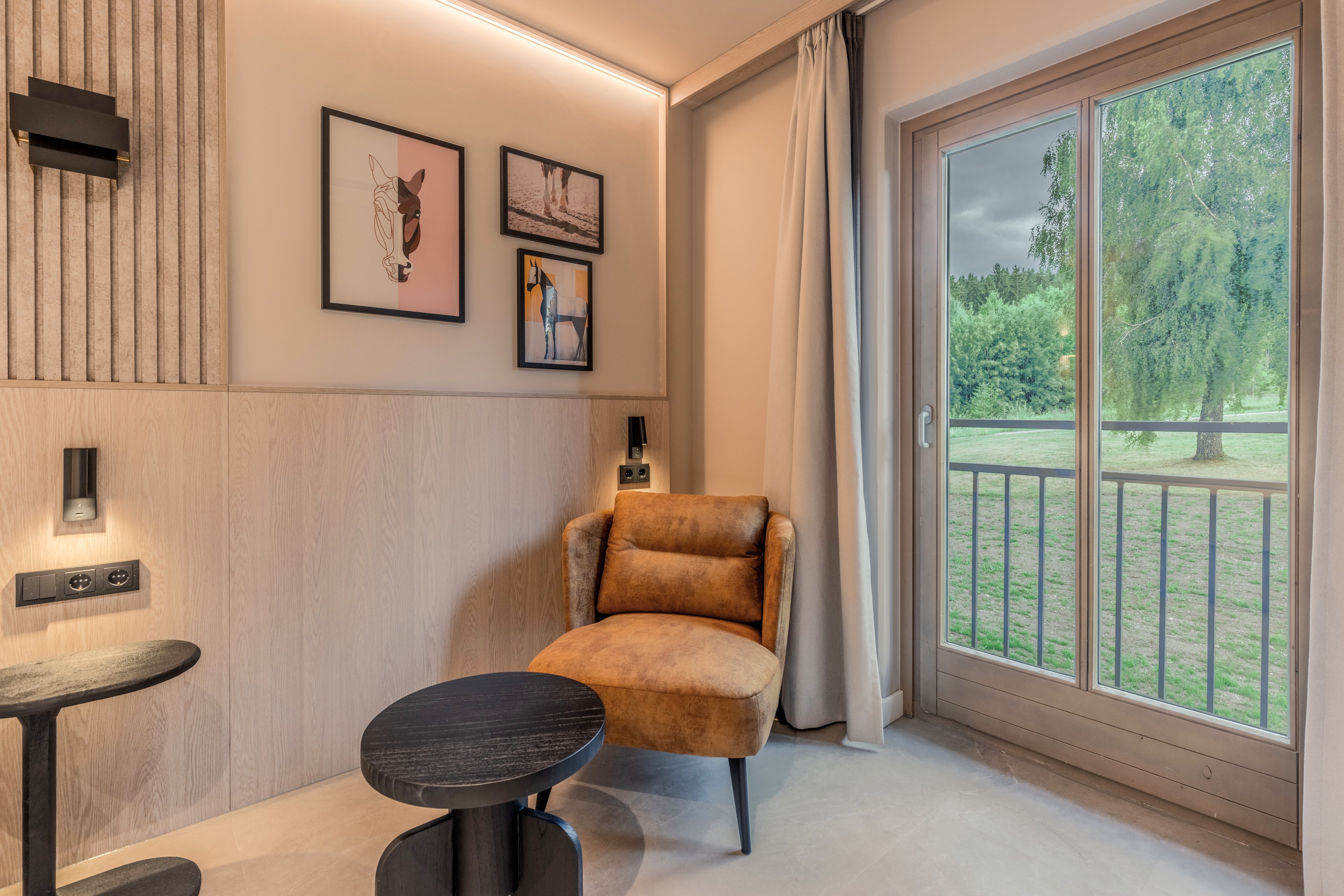 Ein gemütliches Leseecke mit Sesseln, Tischen und blick zur Terrasse mit Naturblick