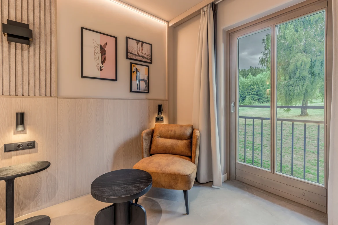 Ein gemütliches Leseecke mit Sesseln, Tischen und blick zur Terrasse mit Naturblick