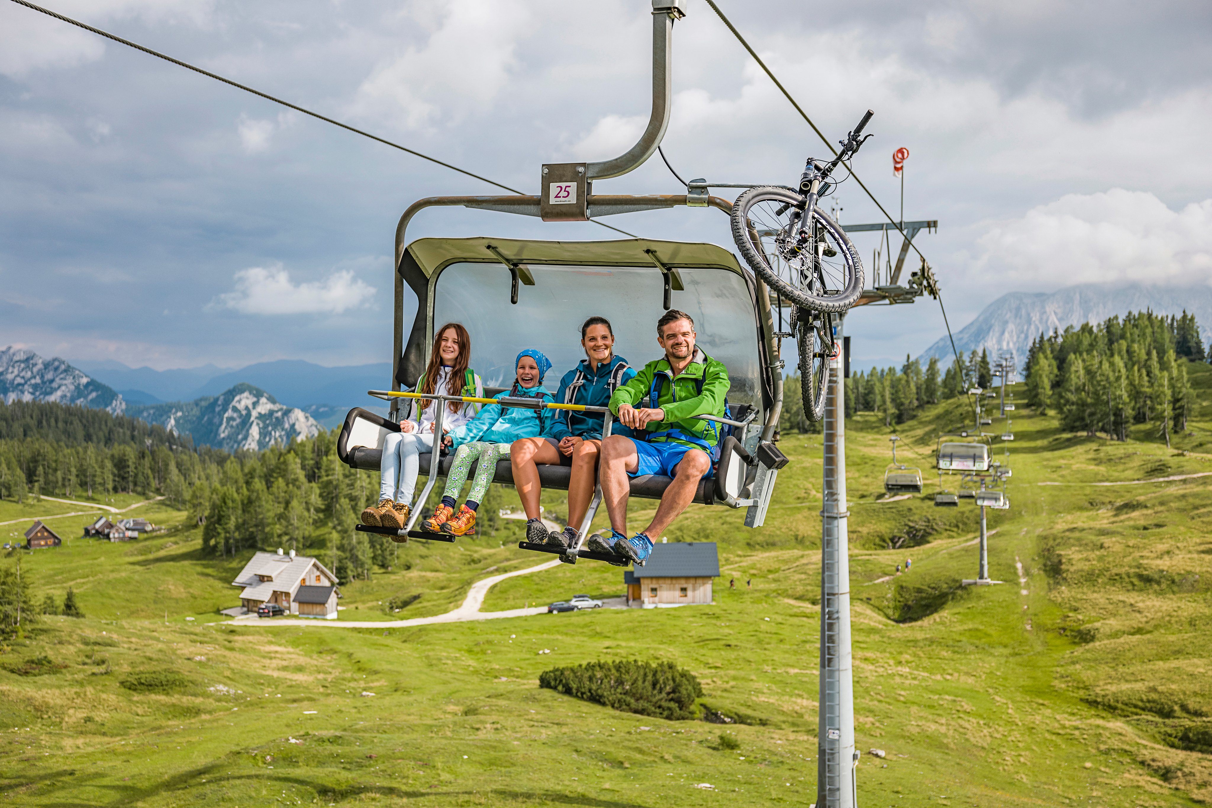 Vier Personen sitzen in einer Gondel der Seilbahn in einer grünen Berglandschaft bei Aldiana Premium Cluburlaub