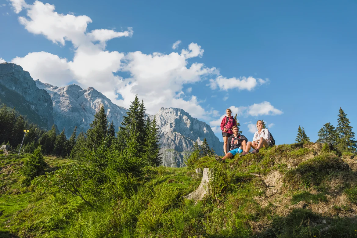 Drei Personen sitzen in einer Bergkulisse und freuen sich