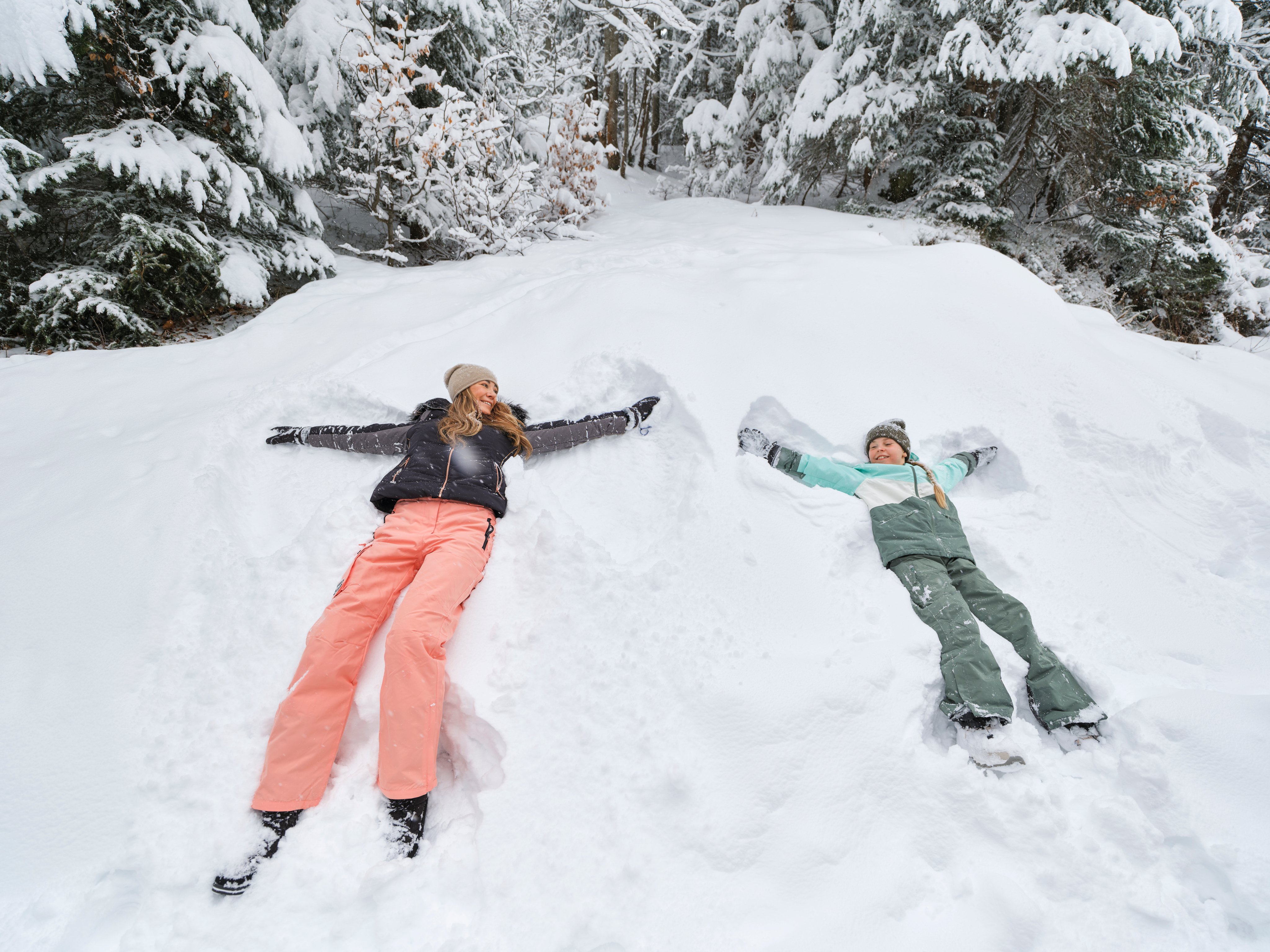Zwei Kinder machen im Schnee eine Schneefigur im Winterwald bei Aldiana Urlaub