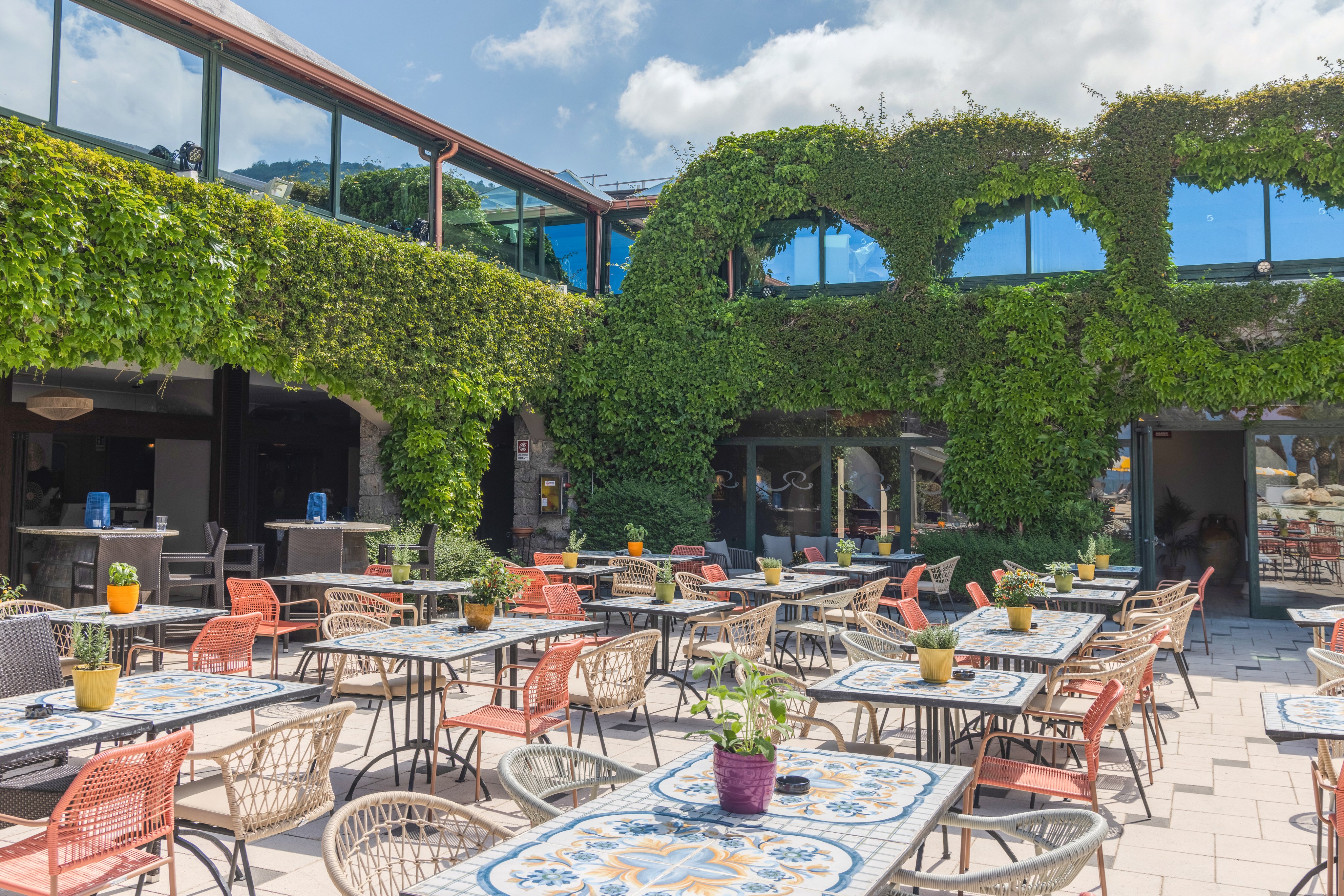 Sonniger Außenbereich eines Premium Clubhotels mit Tischen und grünen Pflanzen, ideal für Entspannung