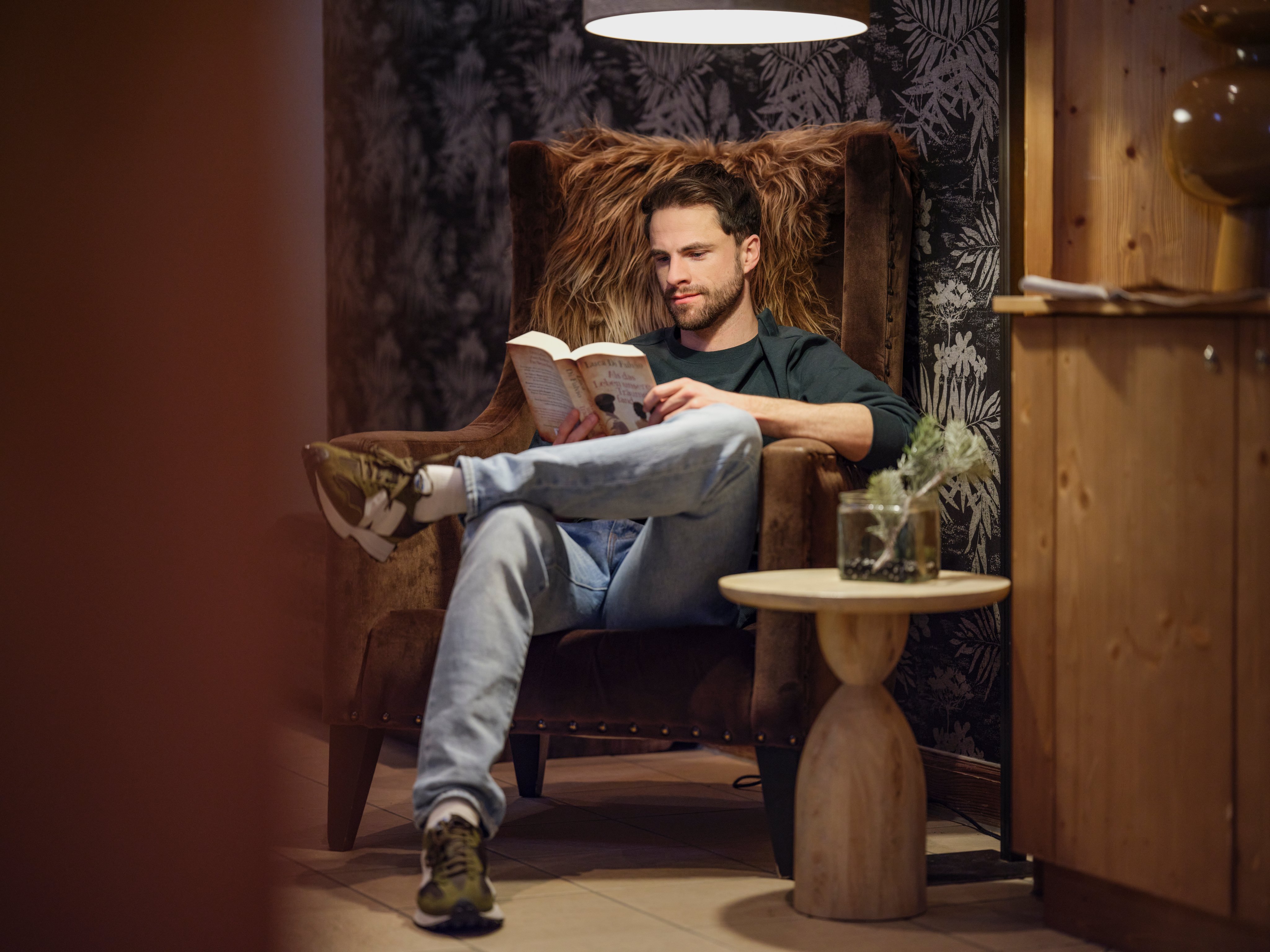 Person liest entspannt in luxurianger Club-Umgebung, gemütliche Atmosphäre, Premium Urlaub.