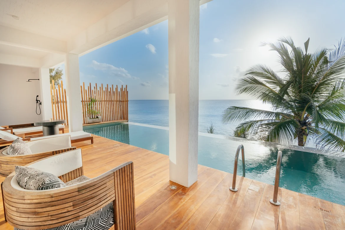 Moderne Pool-Lounge mit Blick auf den Ozean und Palmen bei Sonnenaufgang.