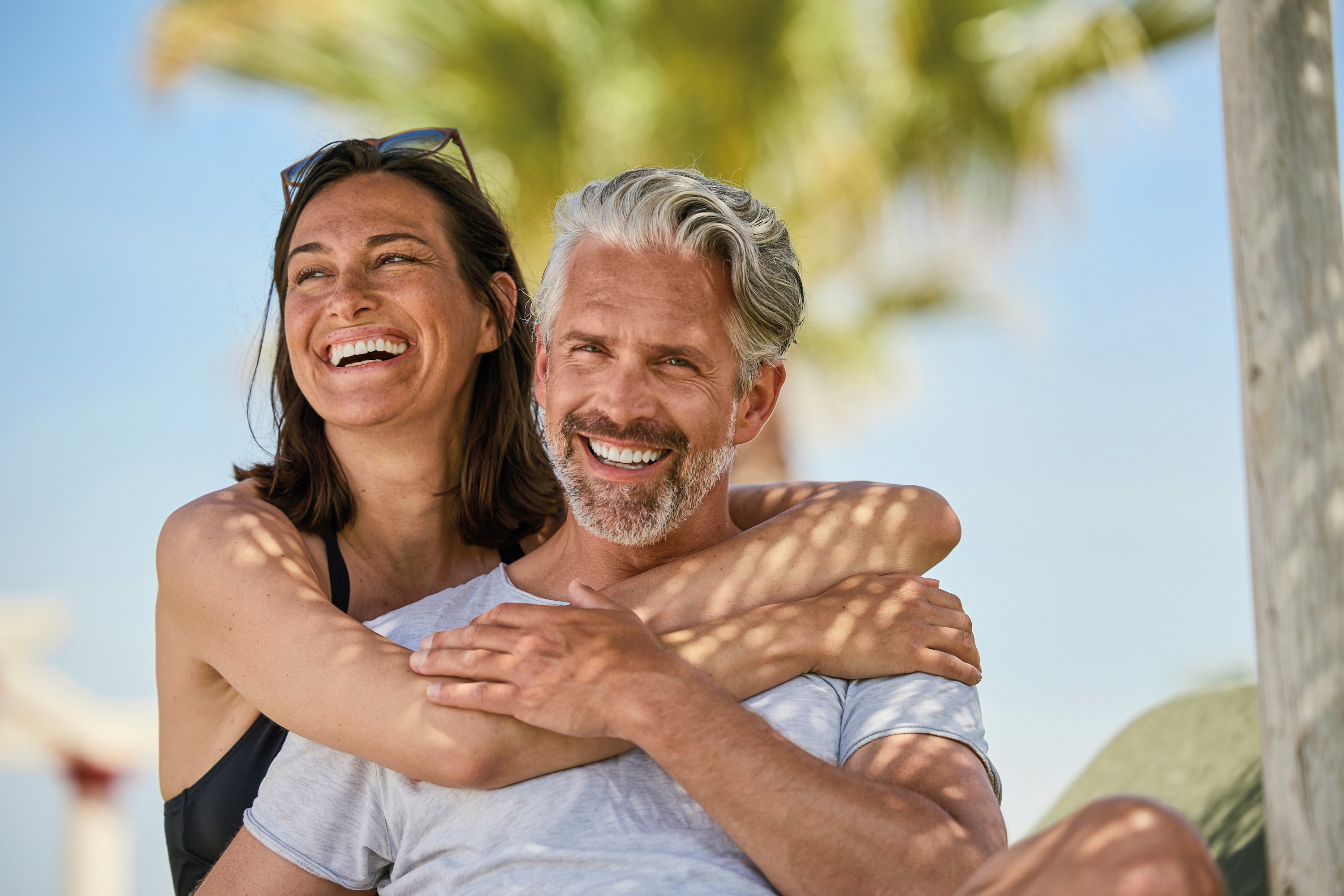 Zwei Personen umarmt am Strand bei Sonnenlicht, entspannter Urlaub im Premium Cluburlaub