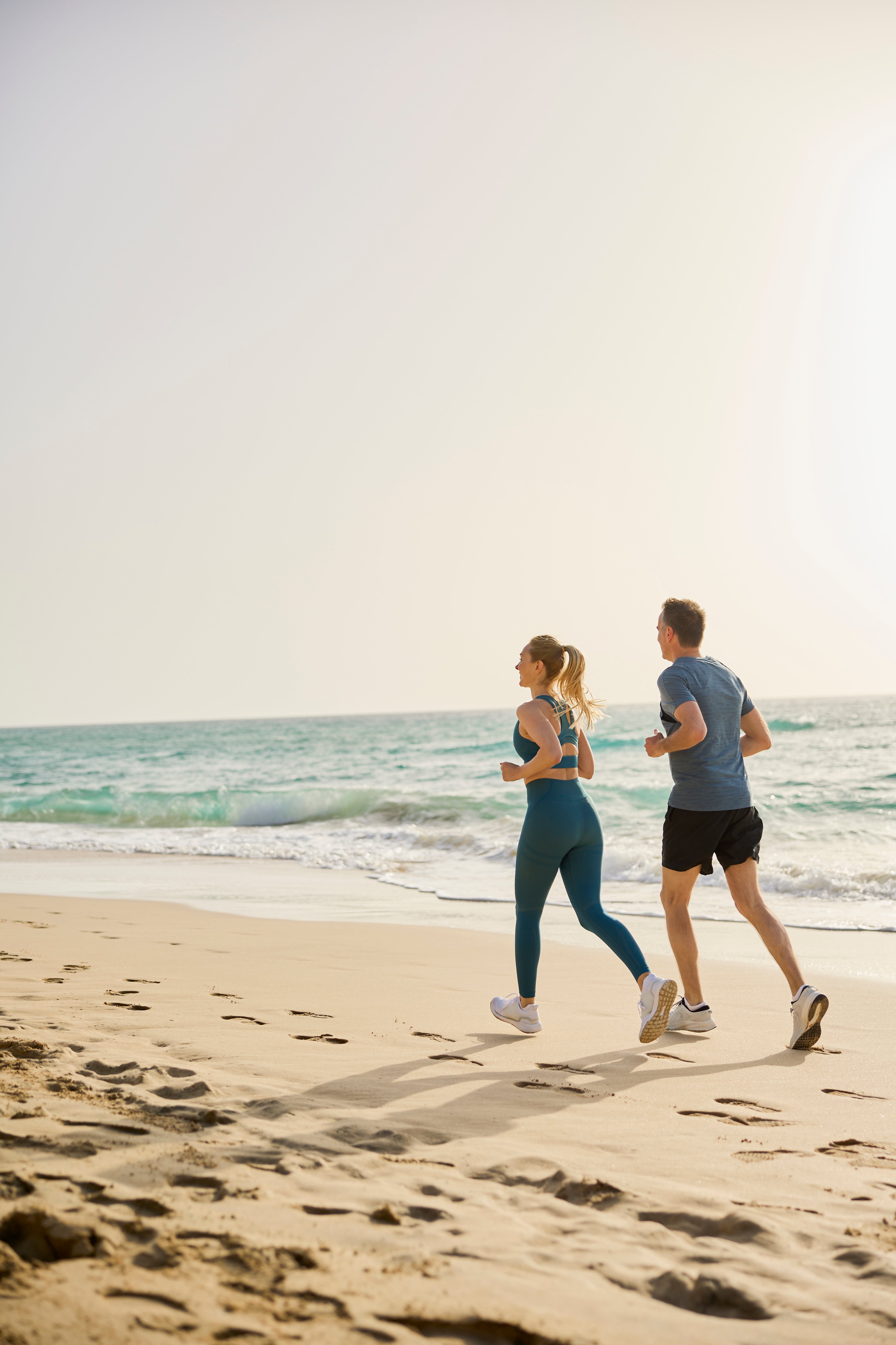 Perfekter Urlaub am Strand mit einem Paar beim Joggen entlang der Küste