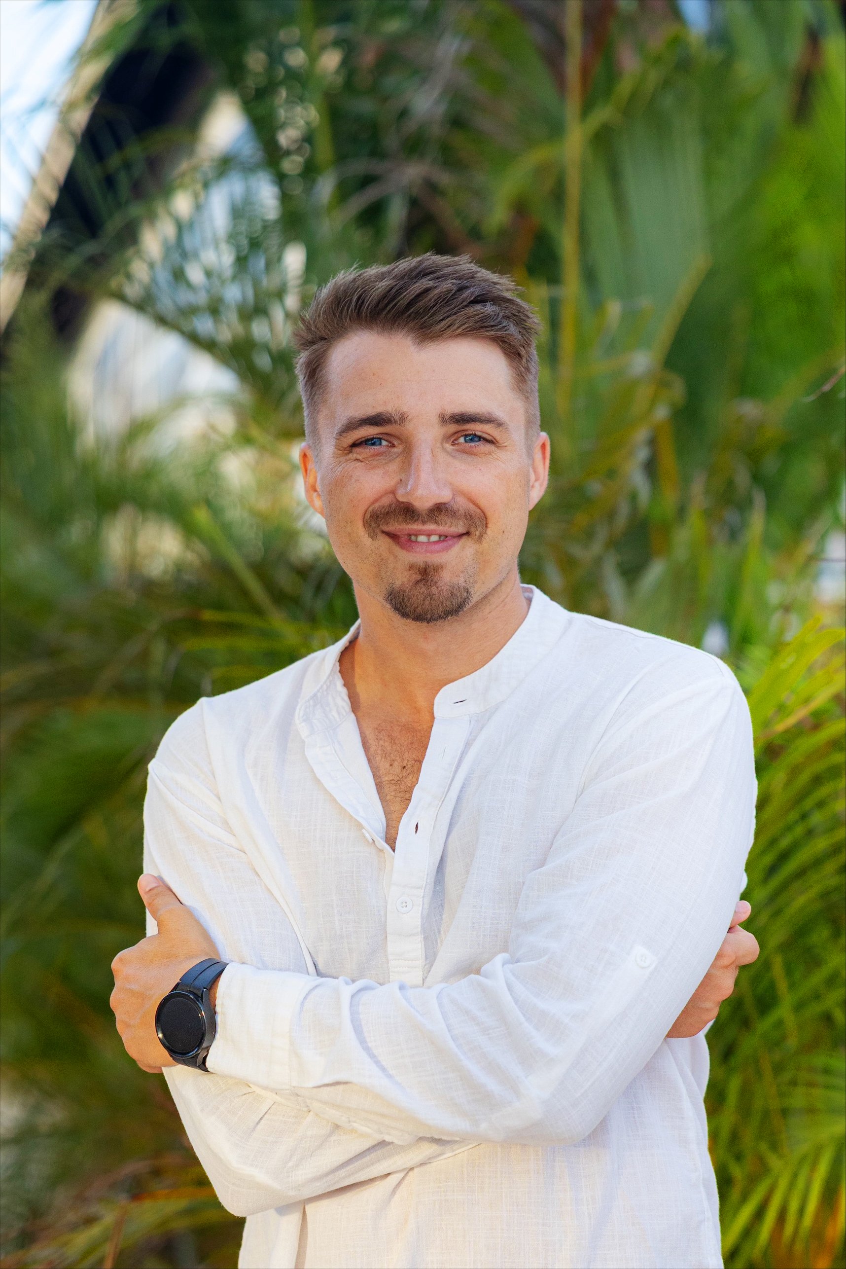 Mann in weißem Hemd vor grünem tropicalem Hintergrund bei Aldiana Premium Cluburlaub
