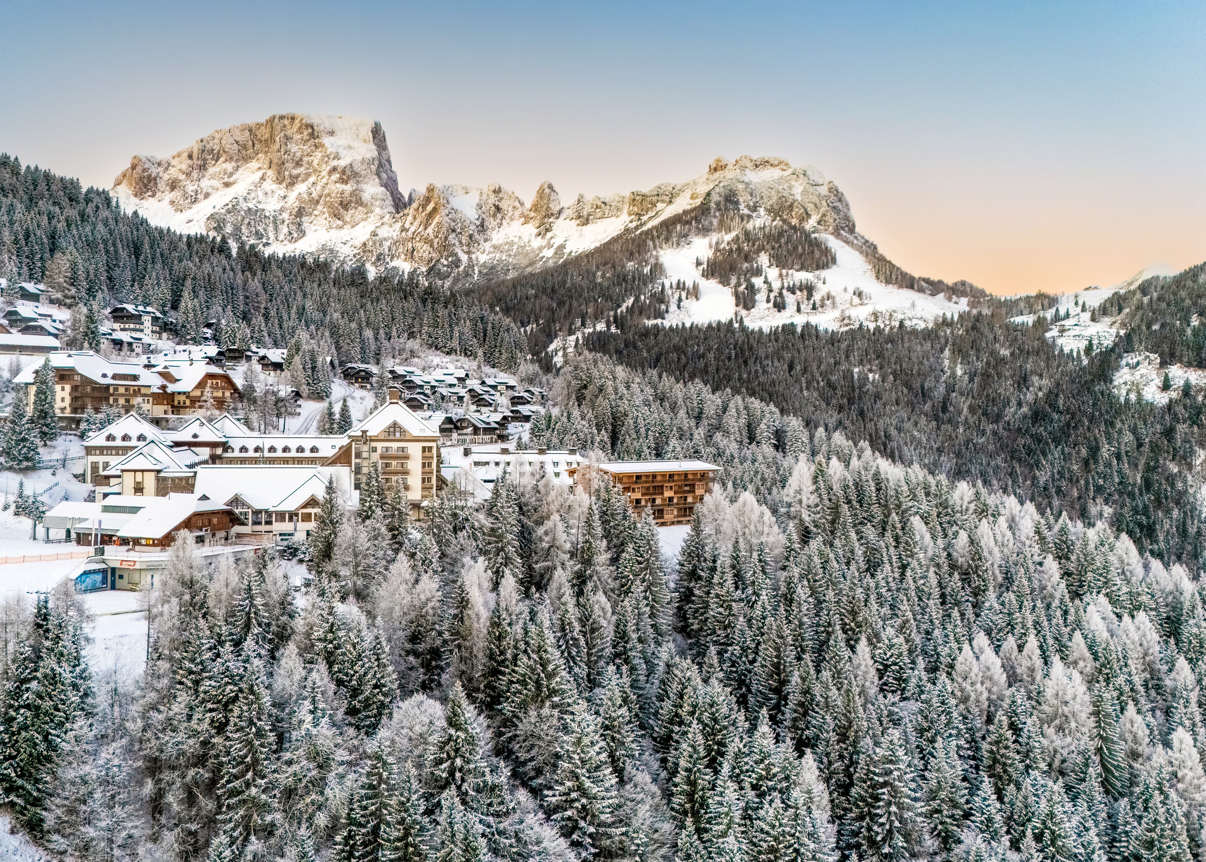 Heller Winterurlaubsort im Schnee mit Bergen und verschneiten Wäldern, attraktiv für Premium Urlaub.