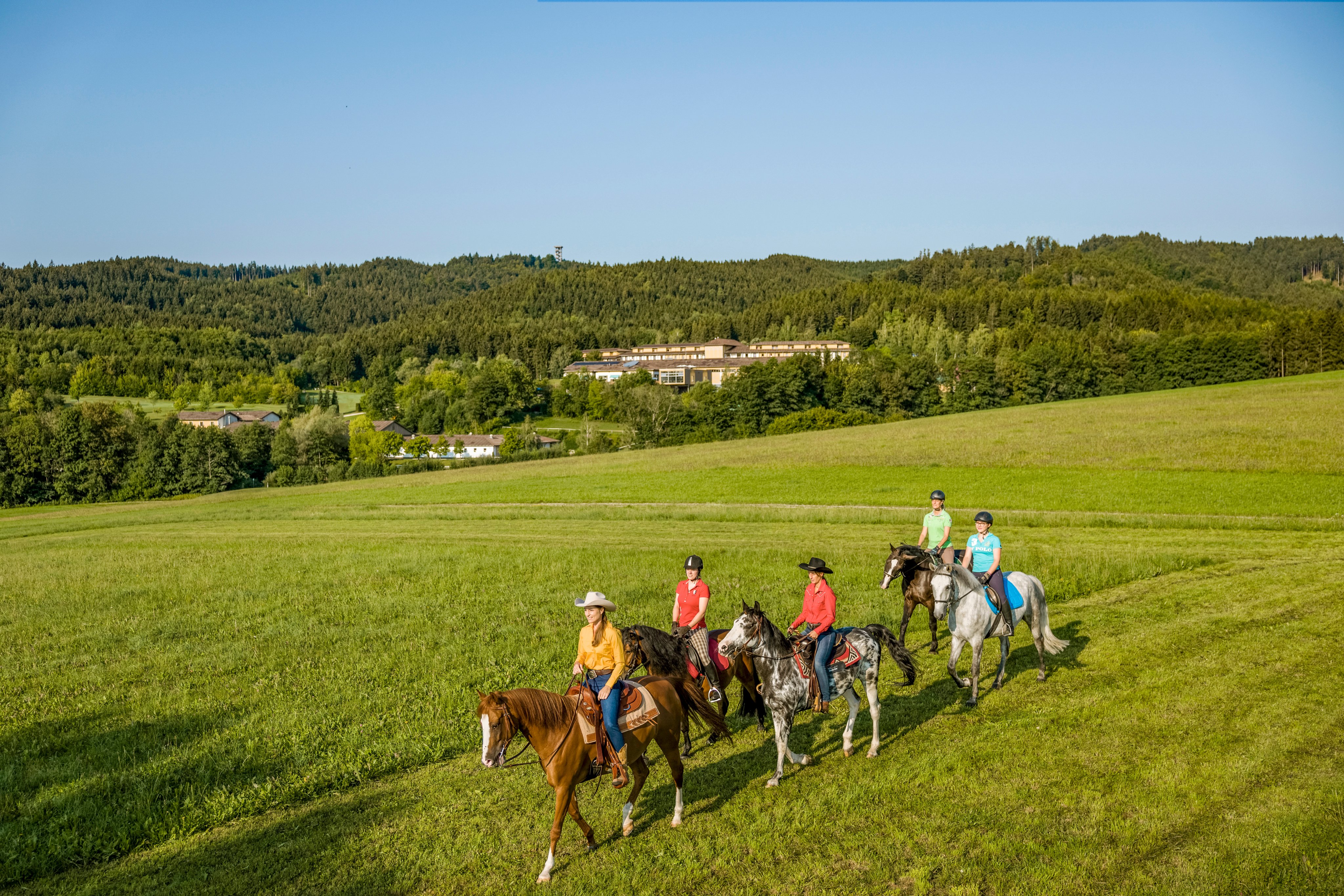 Menschen reiten auf grüner Wiese in idyllischer Natur bei Aldiana Premium Cluburlaub