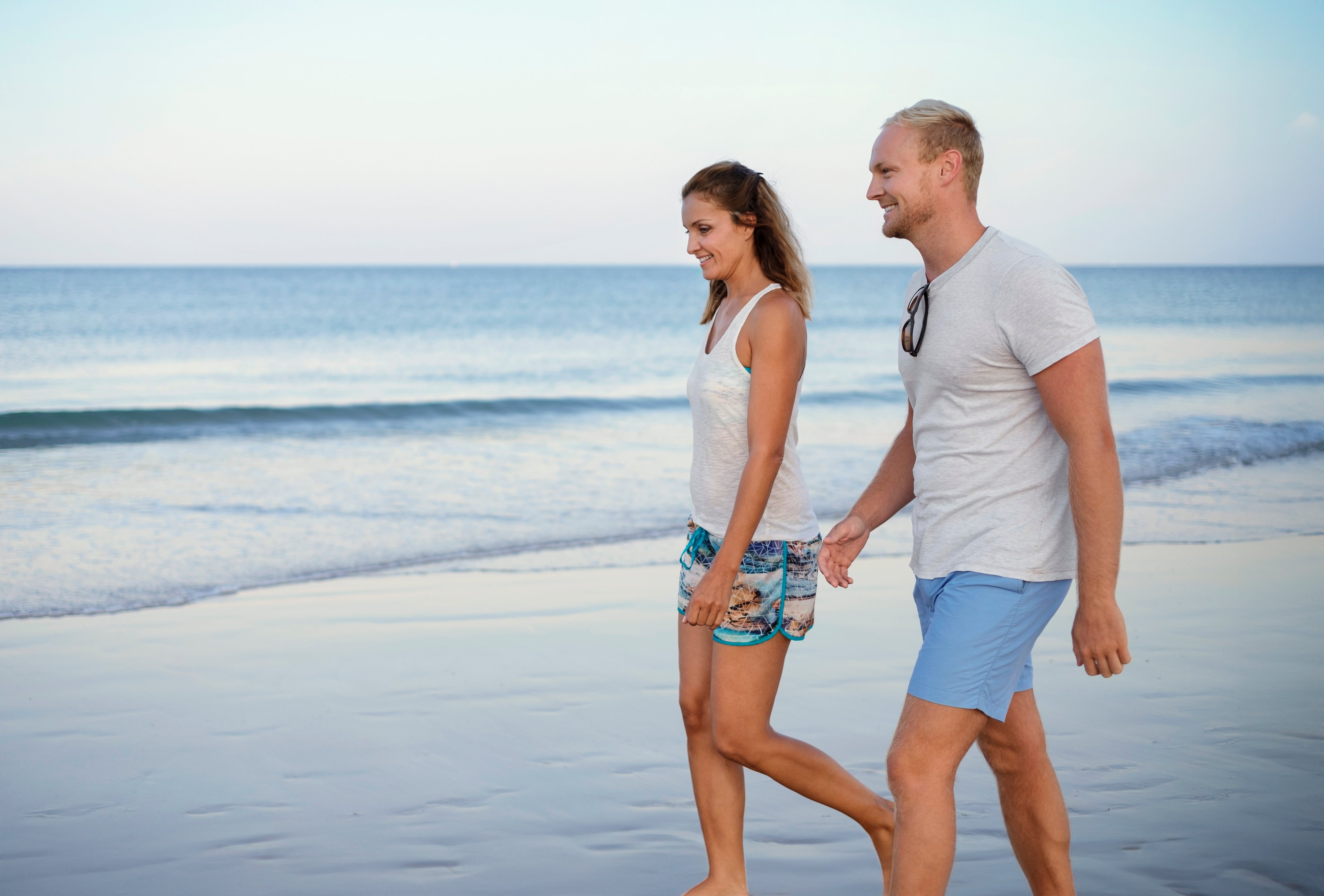 Paar spaziert am Strand in einem Aldiana Premium Cluburlaub, entspannt am Meer