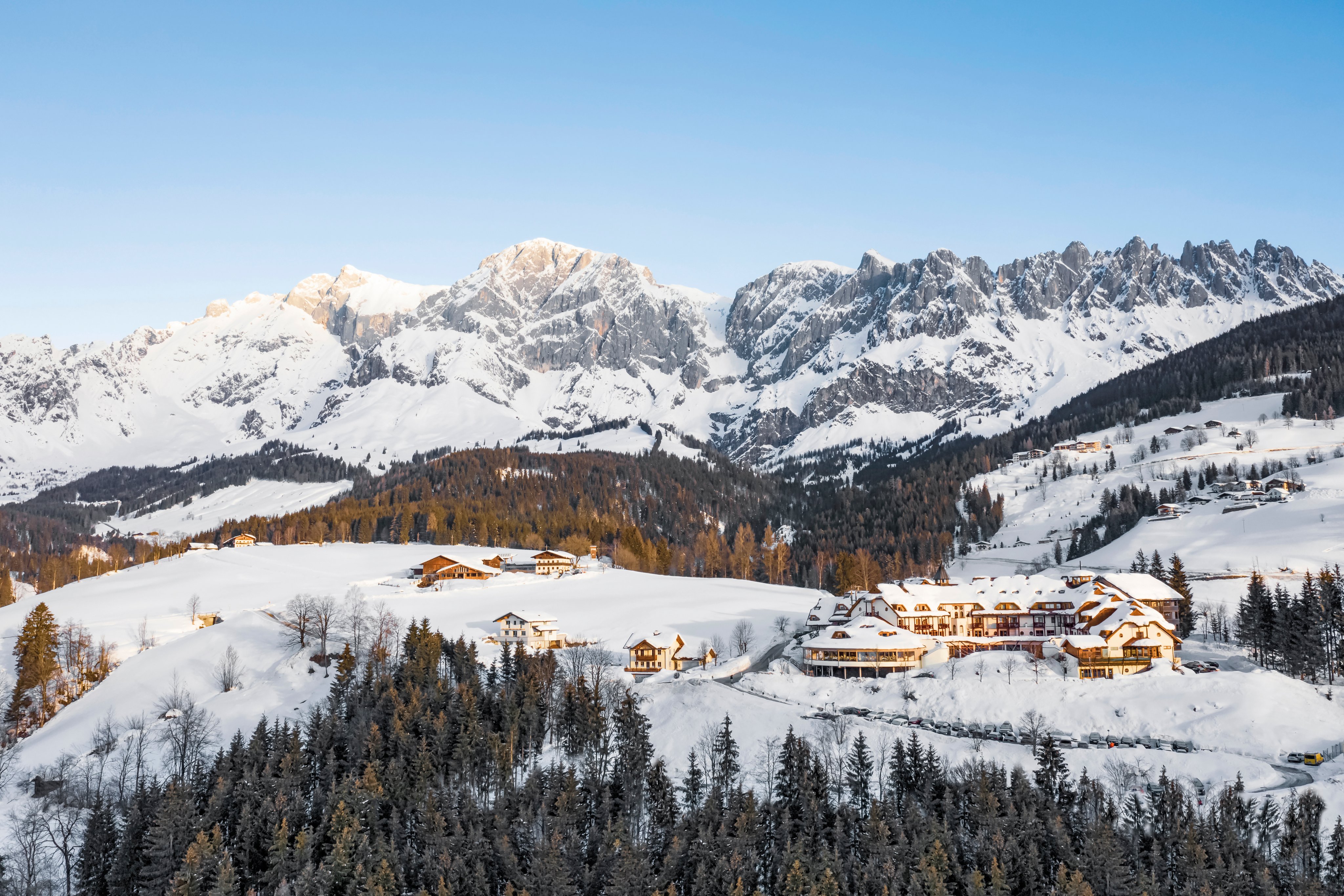 Winterliche Berglandschaft mit Schneebedeckten Häusern und Bergen im Hintergrund