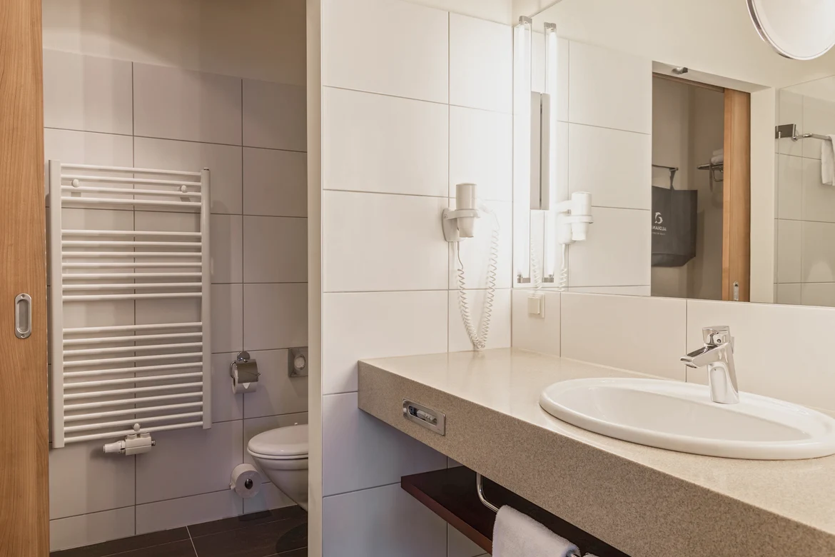 Badezimmer mit Waschbecken, Spiegel, Toilette, Handtuchheizung und moderner Ausstattung