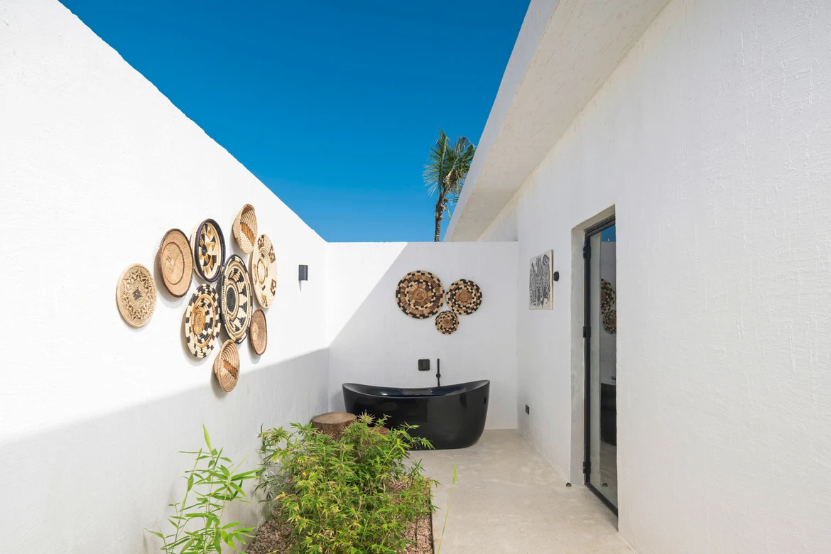 Ein moderner Outdoorbereich mit weißen Wänden, Wanddeko und Badewanne, sonniges Wetter