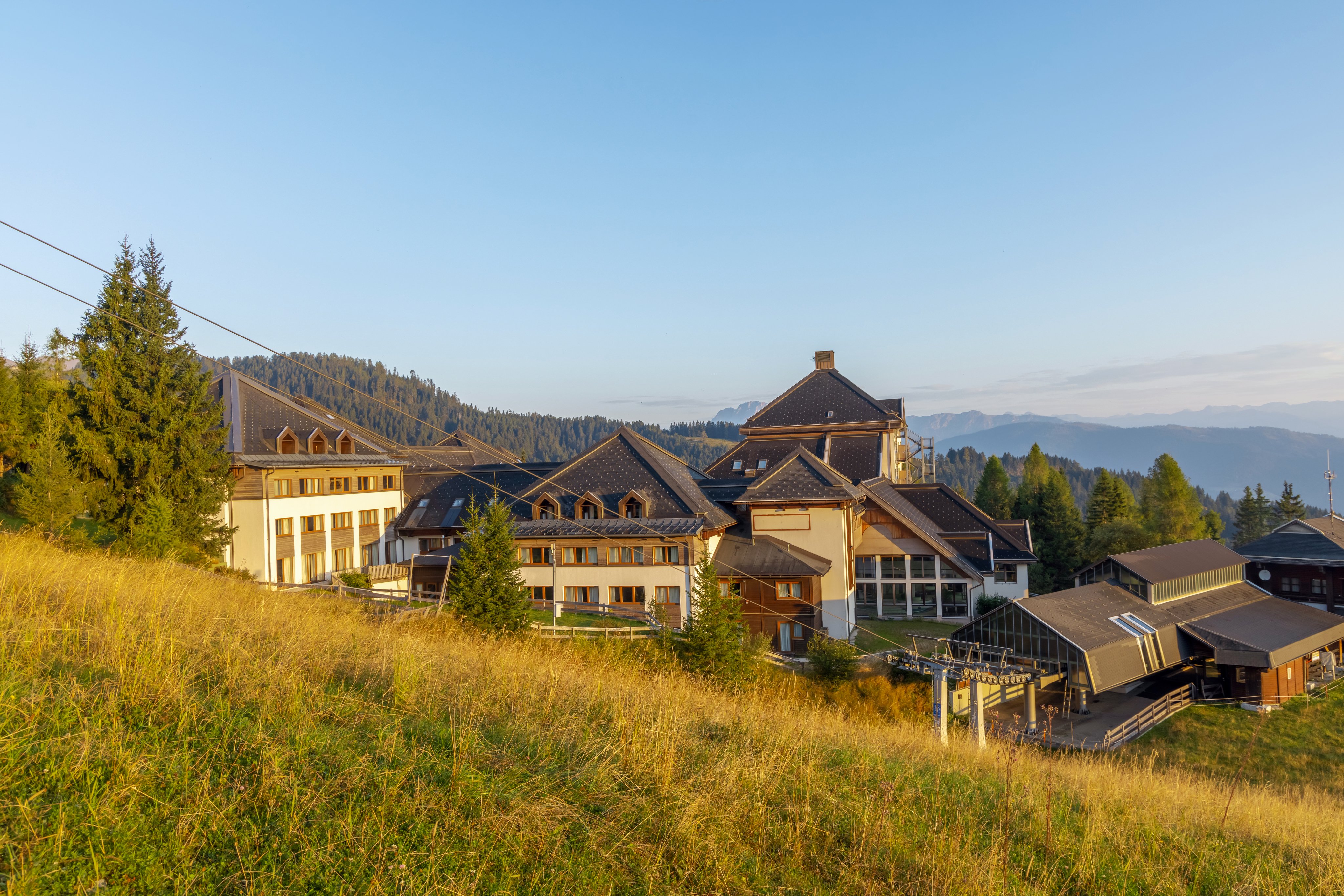 Blick auf ein gepflegtes Premium Cluburlaubsdorf im grünen Bergland, sonniger Tag