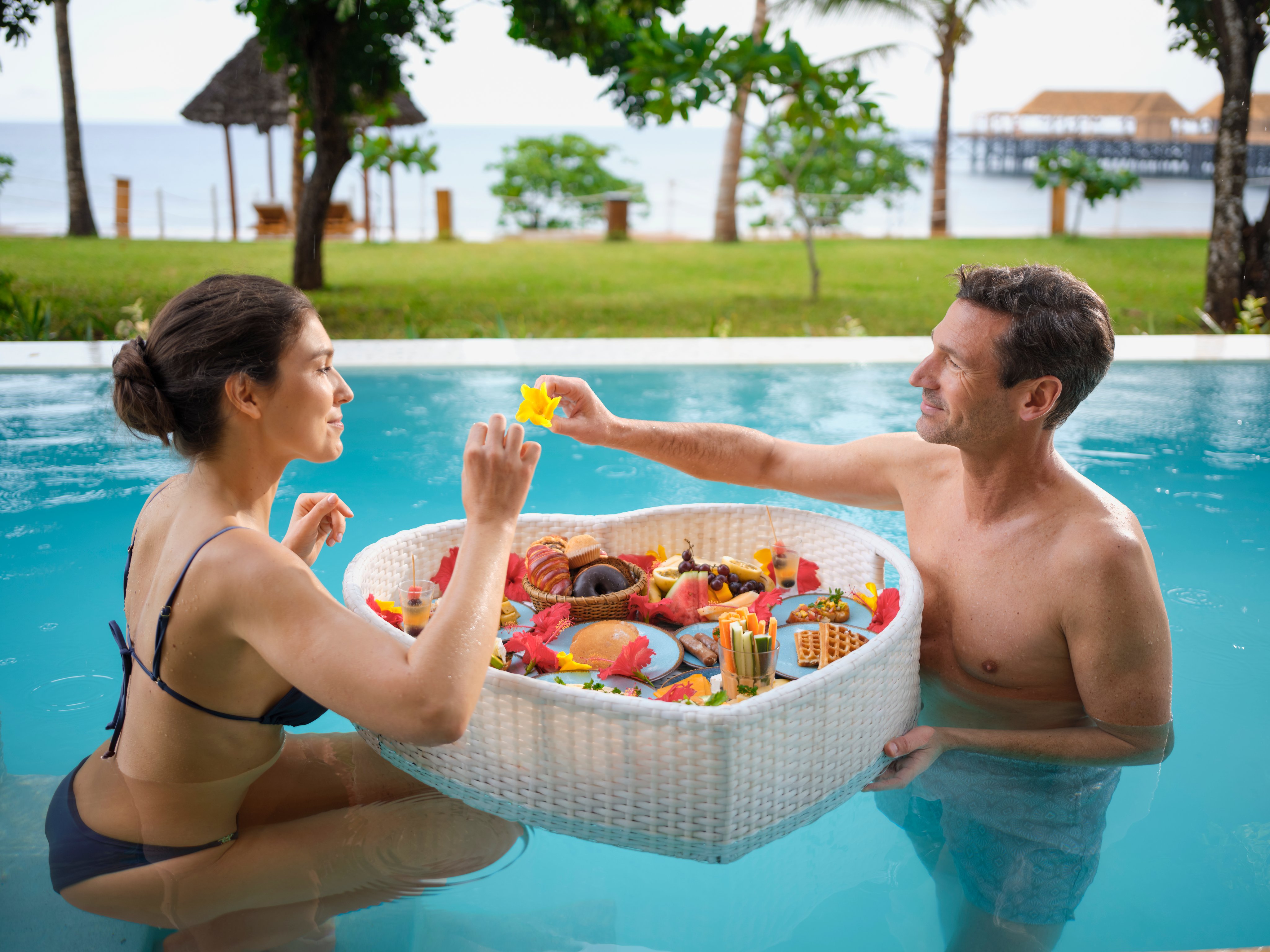 Ein Paar im Pool mit einer Spielzeugkiste im Urlaub am Meer