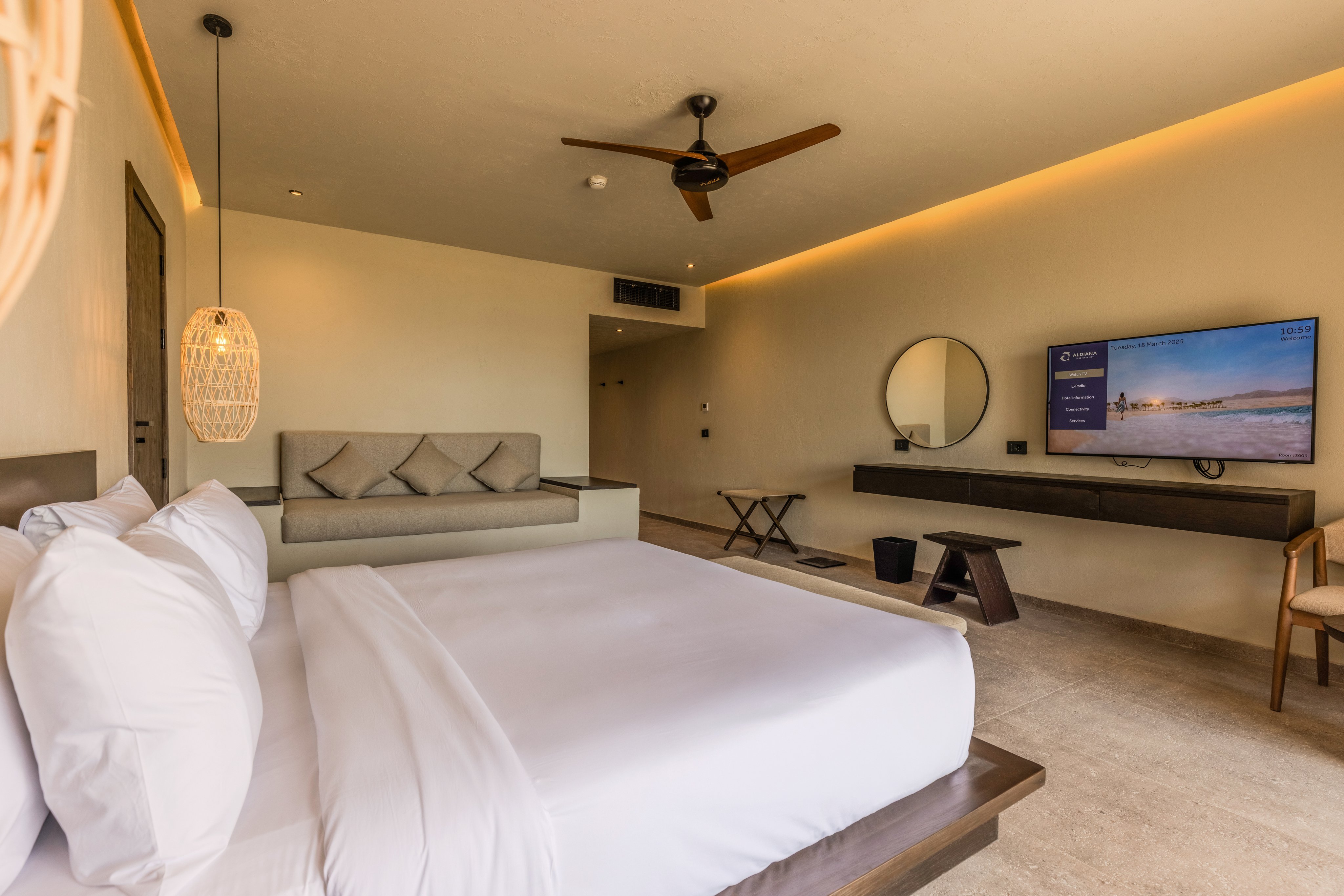 Ein modernes Hotelzimmer mit gemütlichem Bett, TV und Sitzbereich, helle Einrichtung.