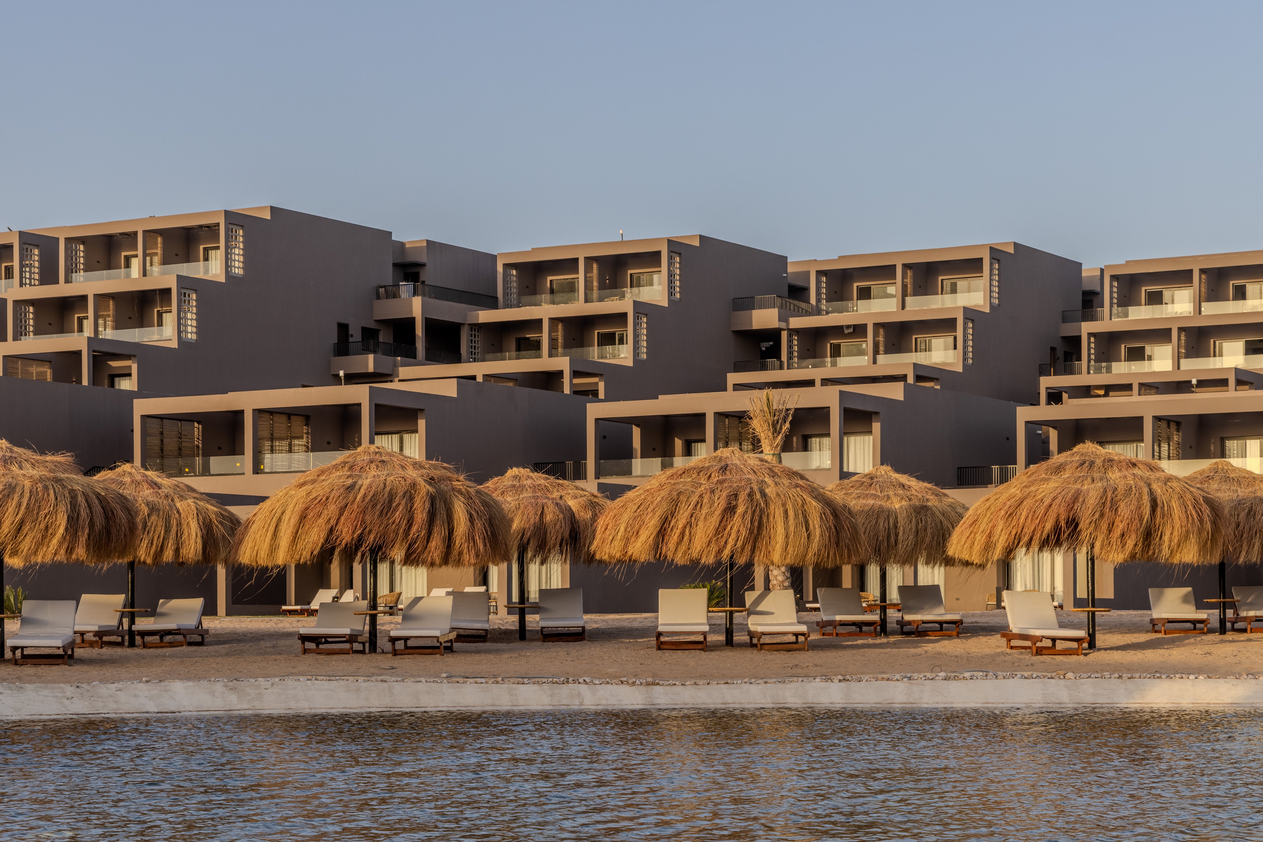Strandurlaub bei Aldiana mit Sonnenliegen und Sonnenschirmen unter Palmen.