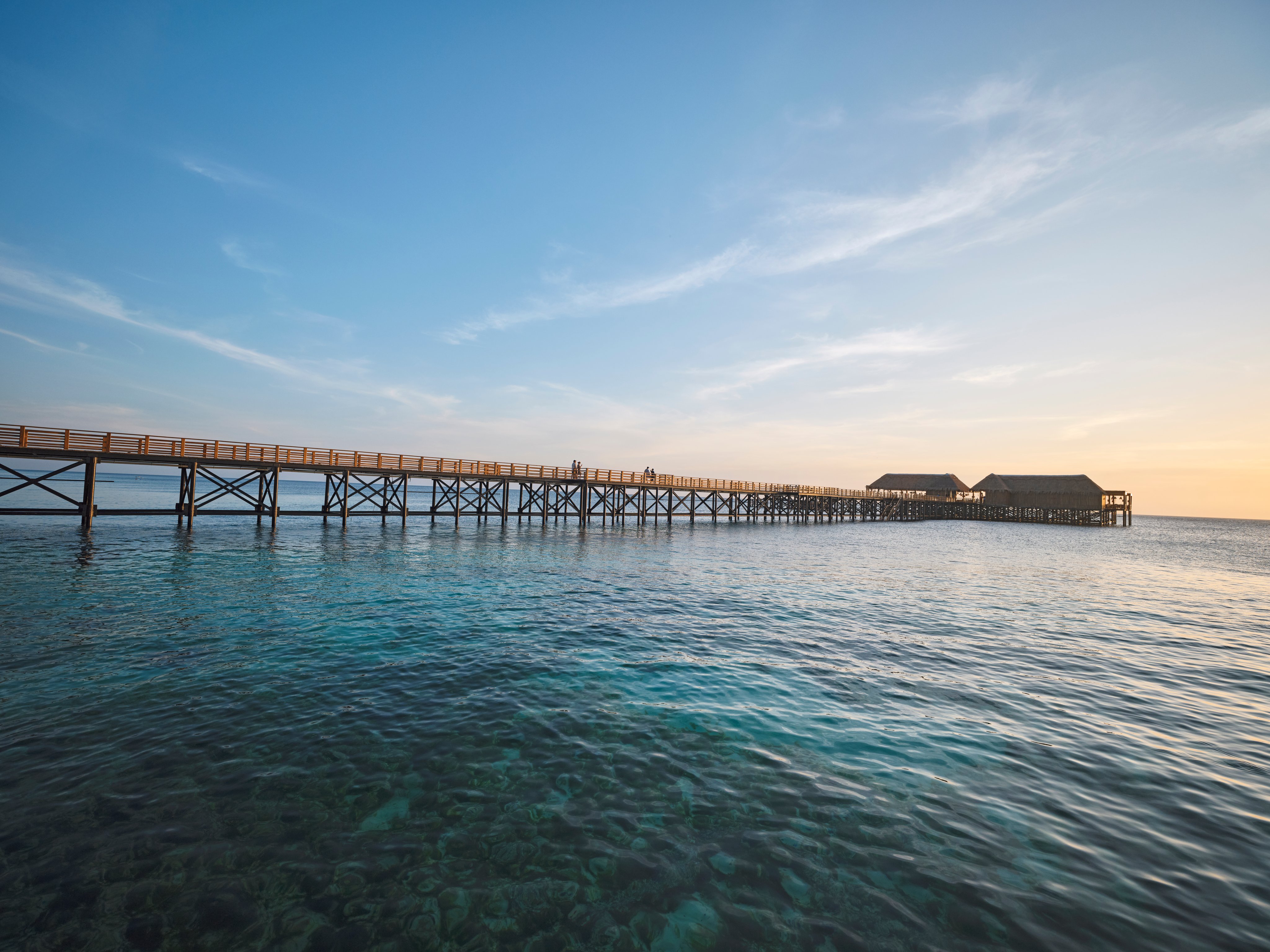 Blick auf einen Holzsteg zum Meer bei Sonnenuntergang bei Aldiana Premium Cluburlaub