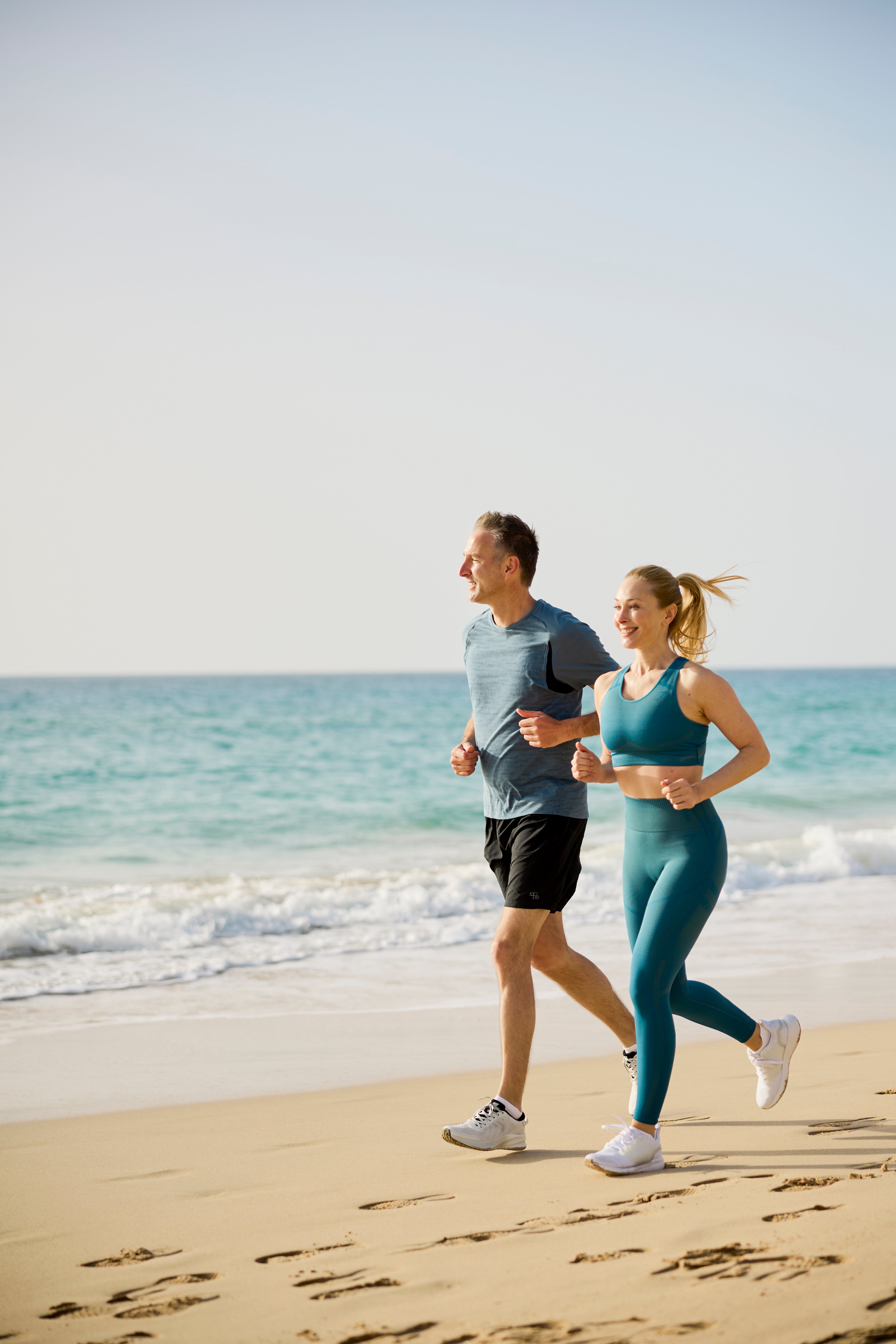 Zwei joggende Personen am Strand bei Sonnenaufgang, entspannter Premium Cluburlaub bei Aldiana