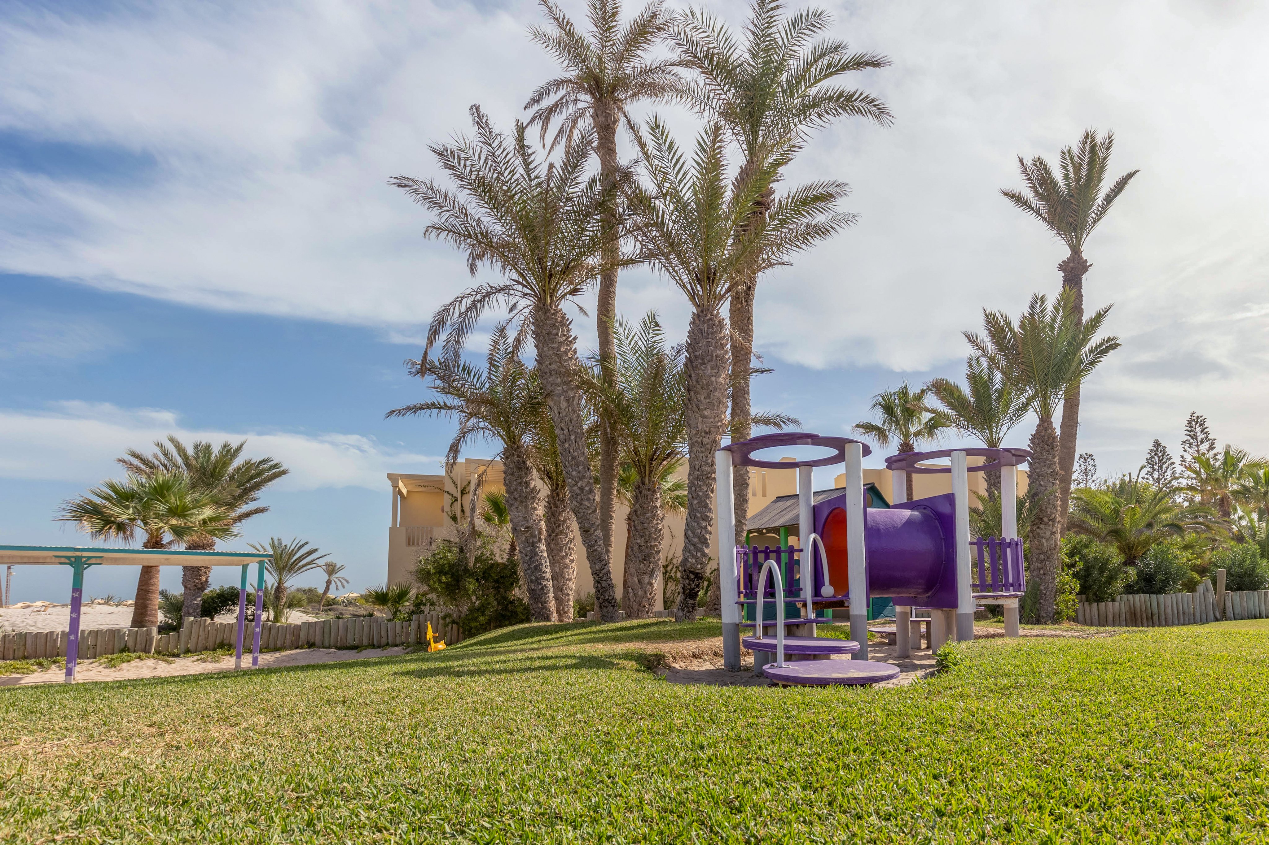 Spielplatz mit Palmen und grünem Rasen bei Aldiana, hochwertiger Cluburlaub in sonniger Lage