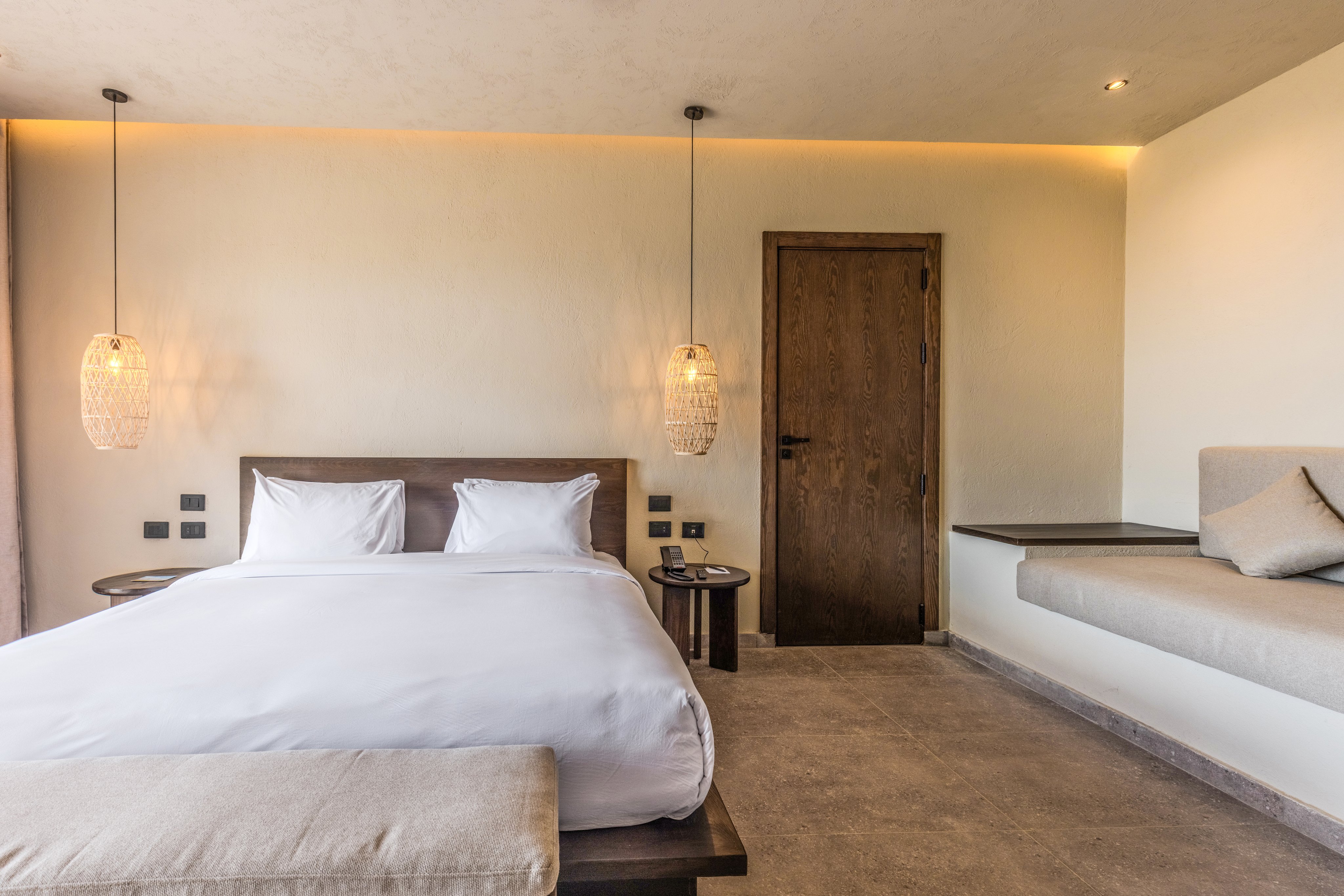 Gemütliches Hotelzimmer mit Doppelbett, Leseecke und stylischer Beleuchtung.