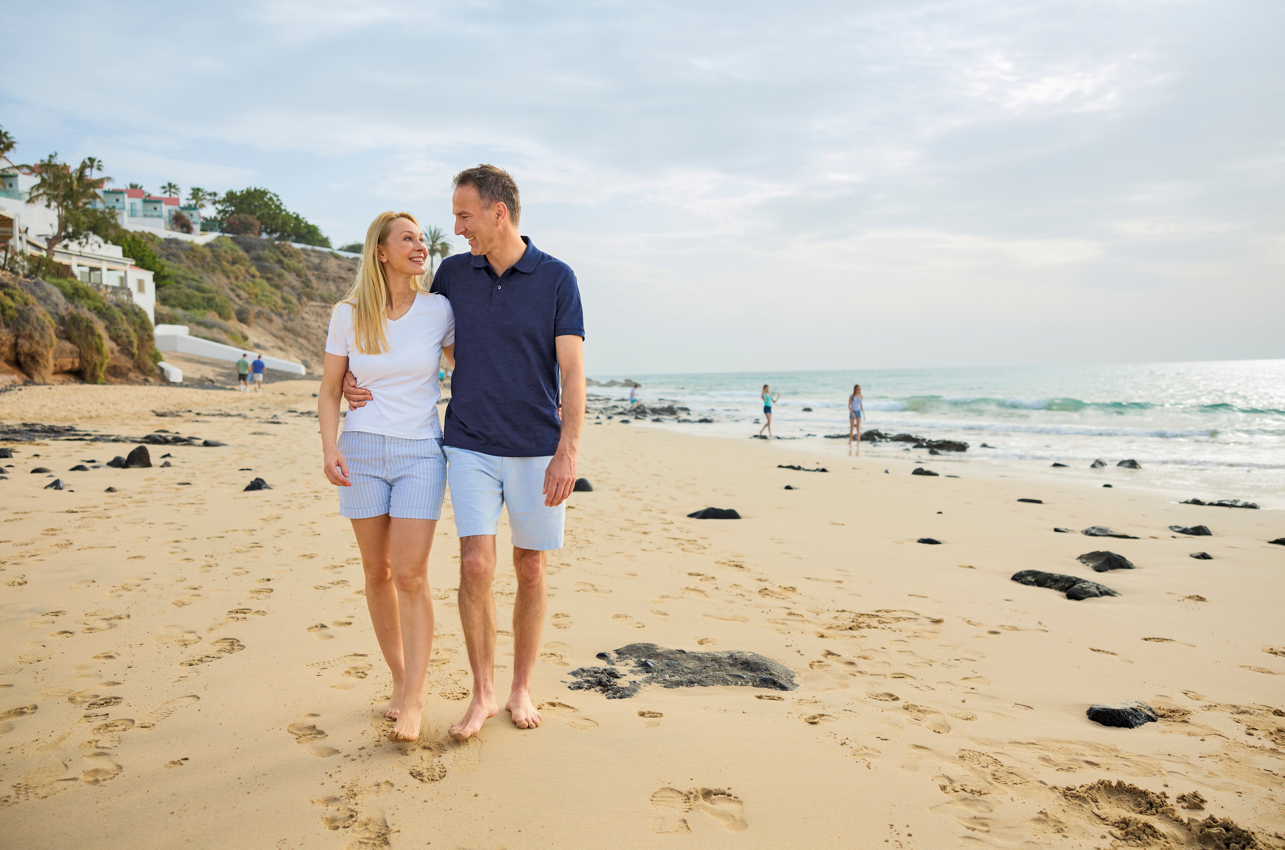 Paar spaziert am Strand bei Sonnenuntergang, entspannter Urlaub bei Aldiana.