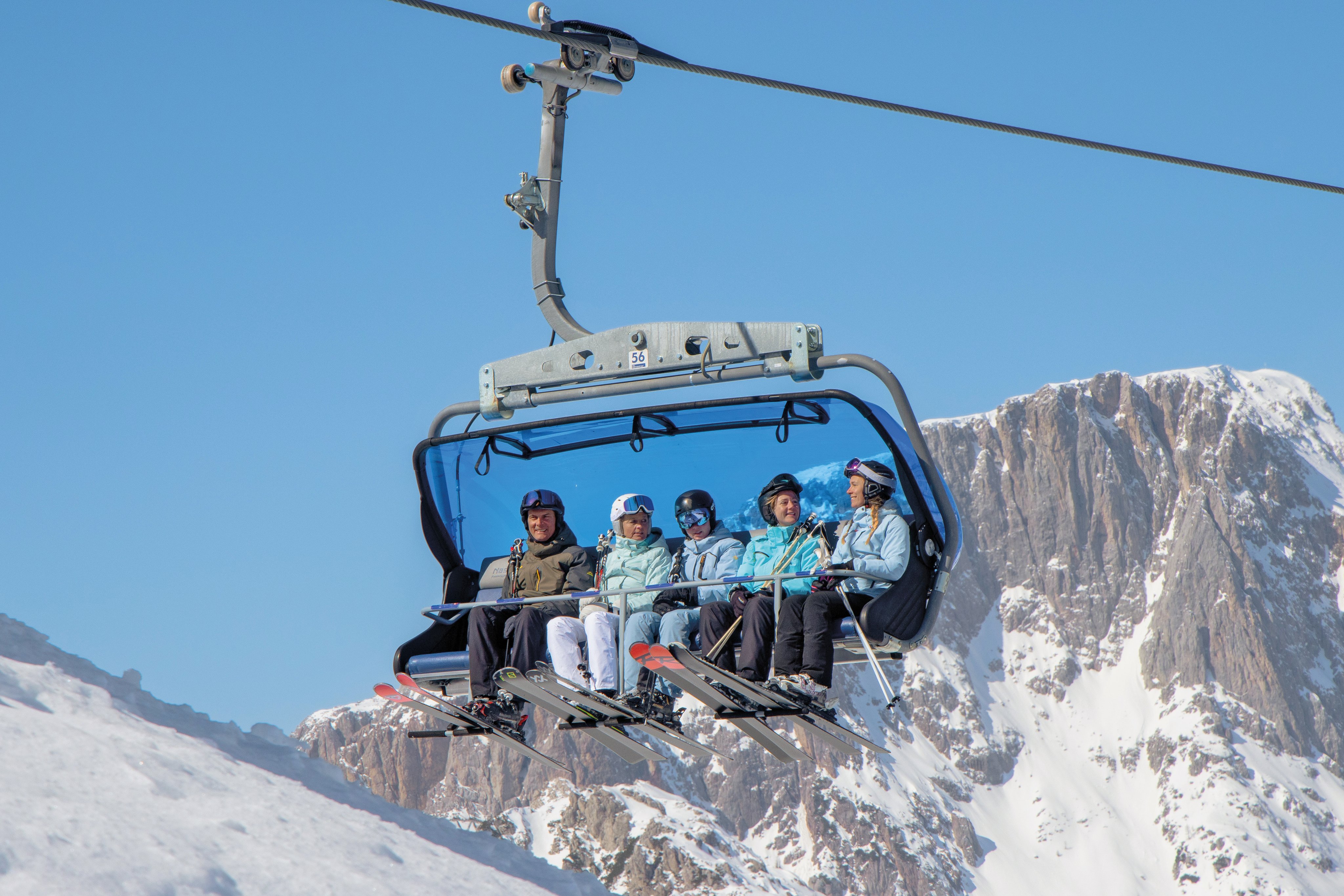 Viersitzer-Skilift mit Berggipfel im Hintergrund, Schnee und klare Himmel, für einen Premium Urlaubsaufenthalt