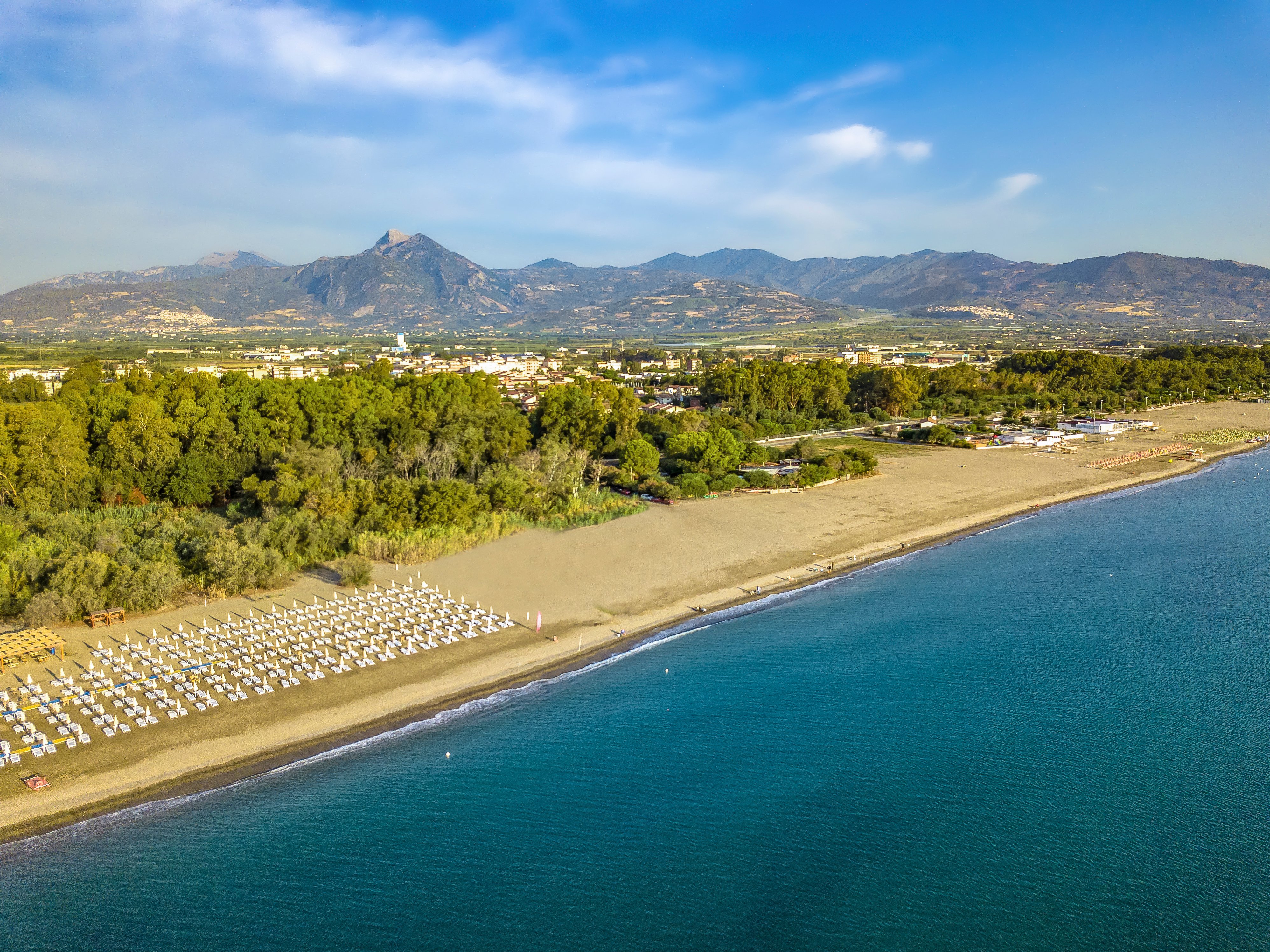 Blick auf den Strand und das Meer bei Aldiana mit Liegestühlen und Bergen im Hintergrund