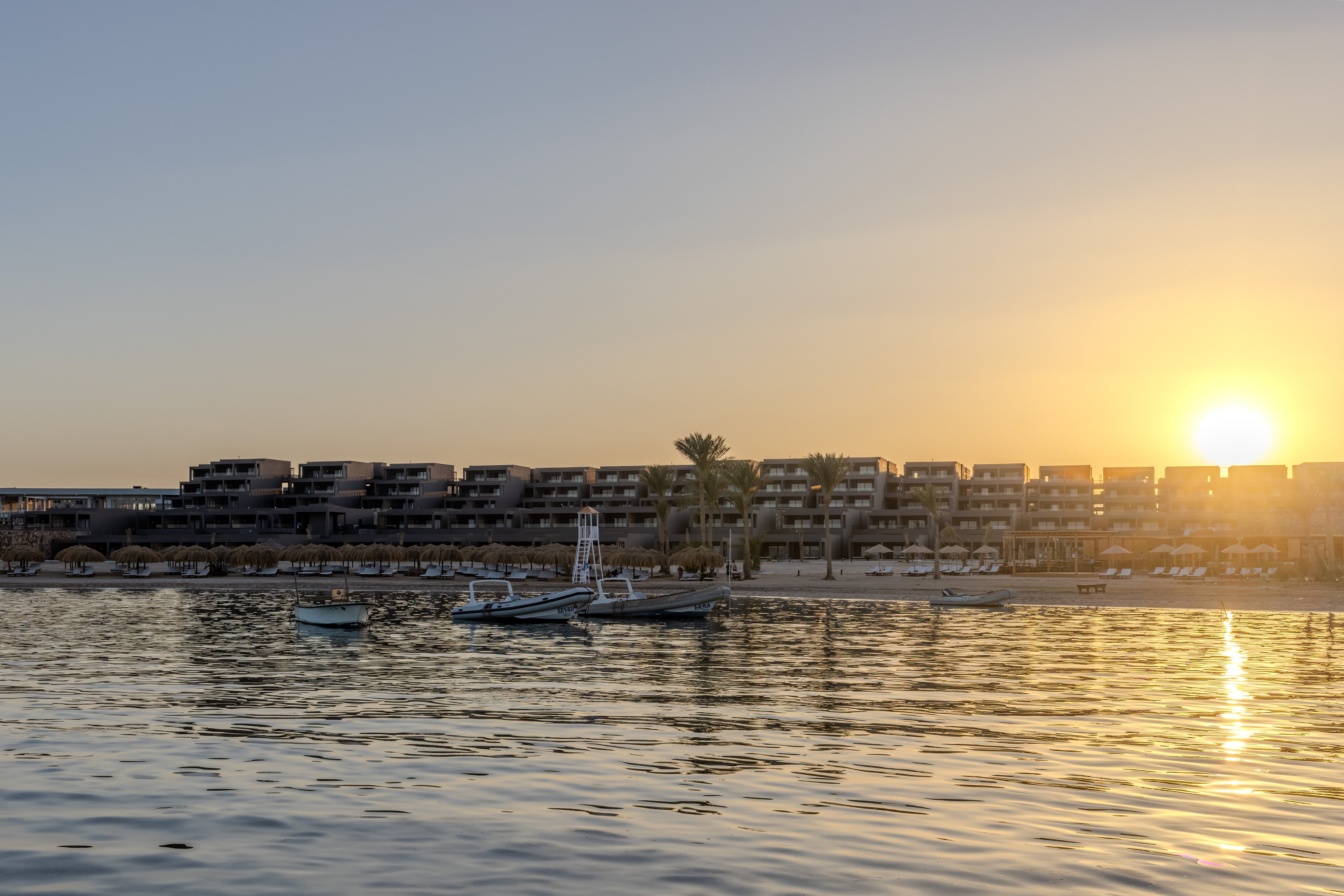 Sonnenuntergang am Hafen mit Booten und Hotelgebäuden im Hintergrund