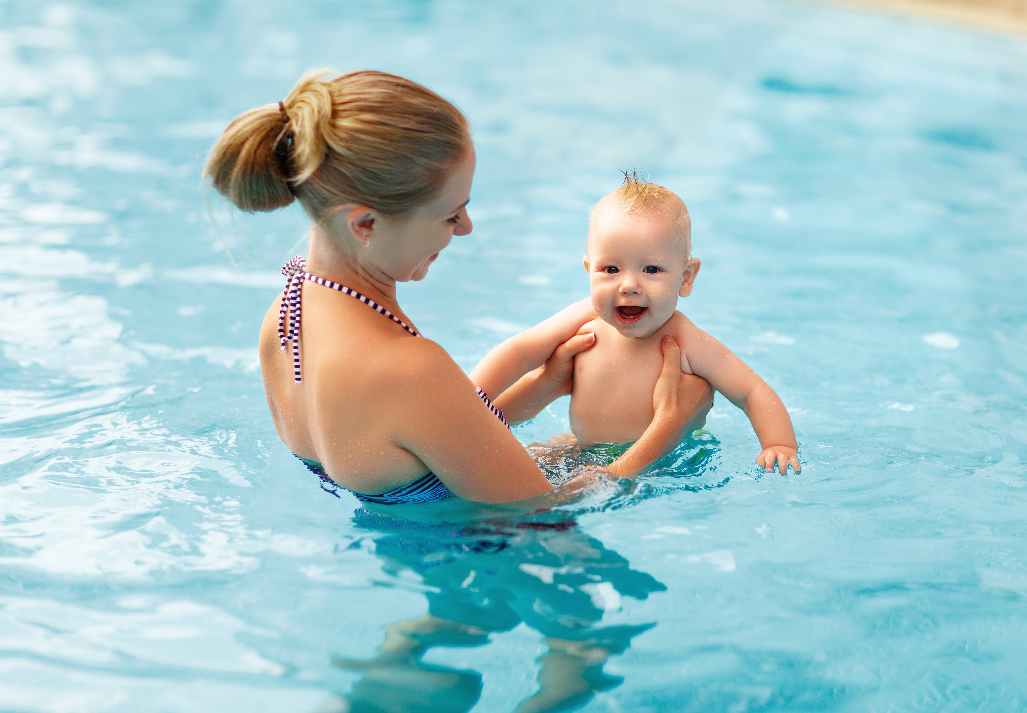 Frau hält Baby im Pool bei einem Premium Aldiana Cluburlaub, Wasserspaß im Urlaub