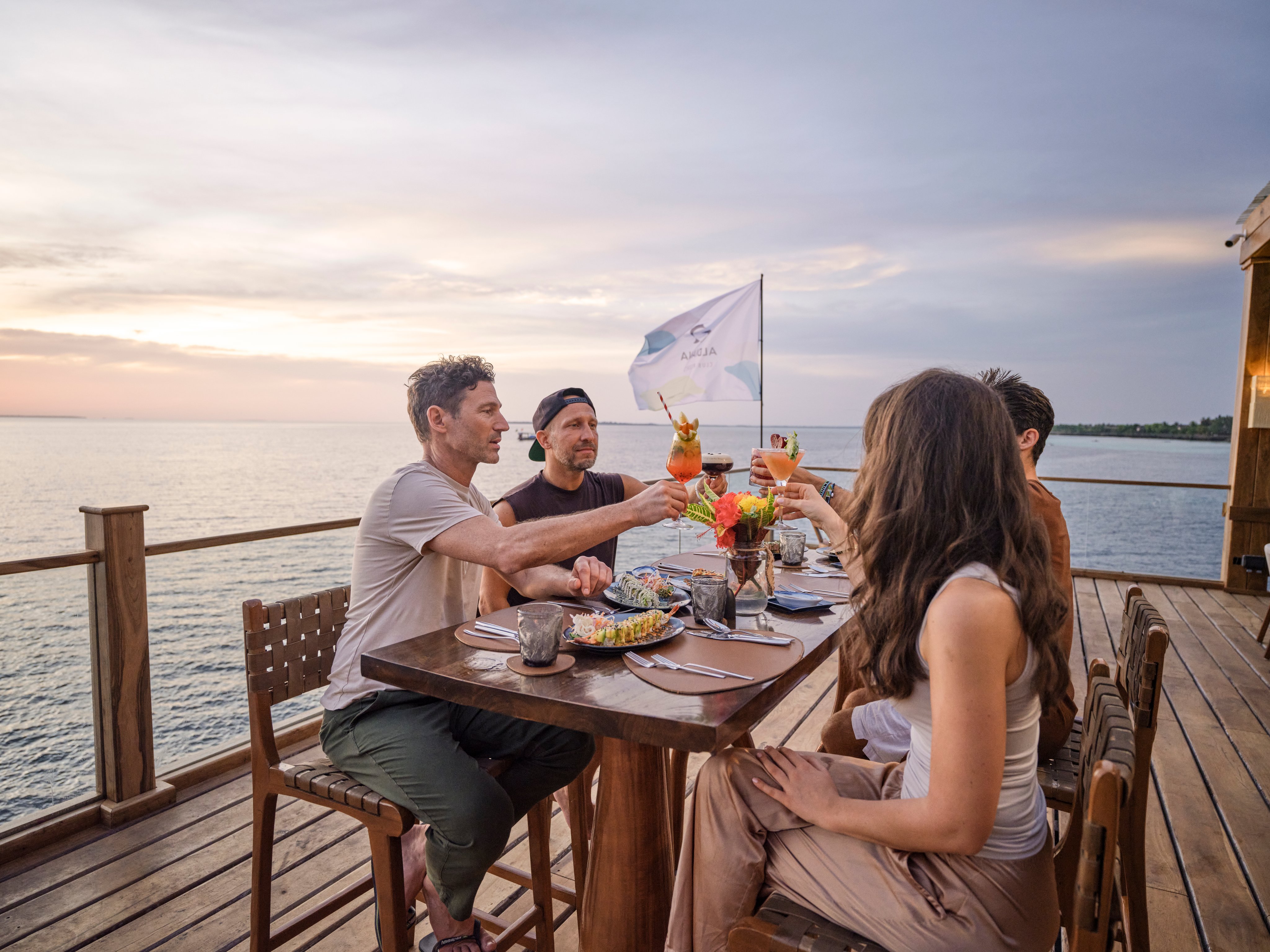 Menschen genießen ein Dinner auf einer Pier mit Blick auf den Sonnenuntergang am See