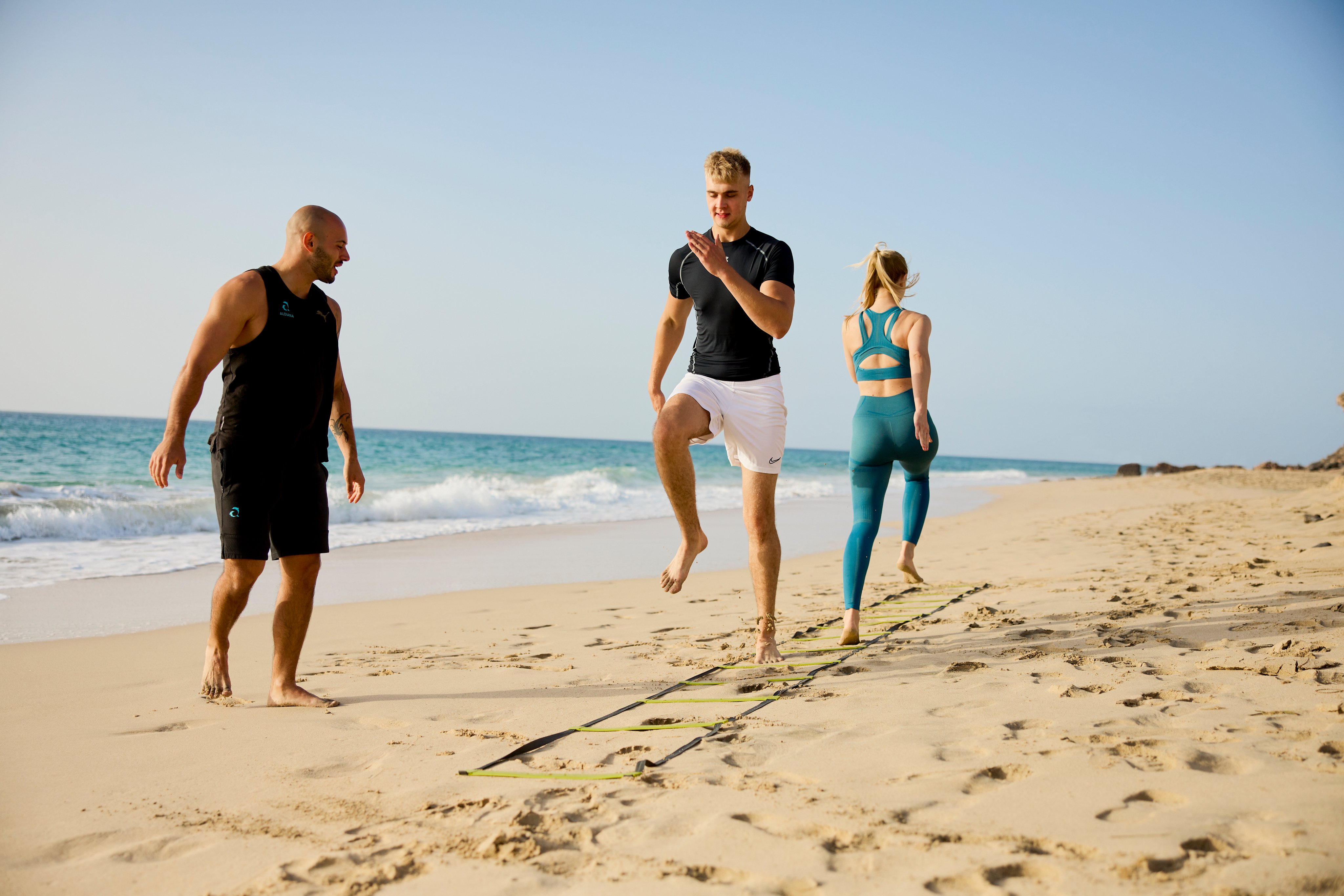 2 Personen mit Trainer am Strand beim Workout