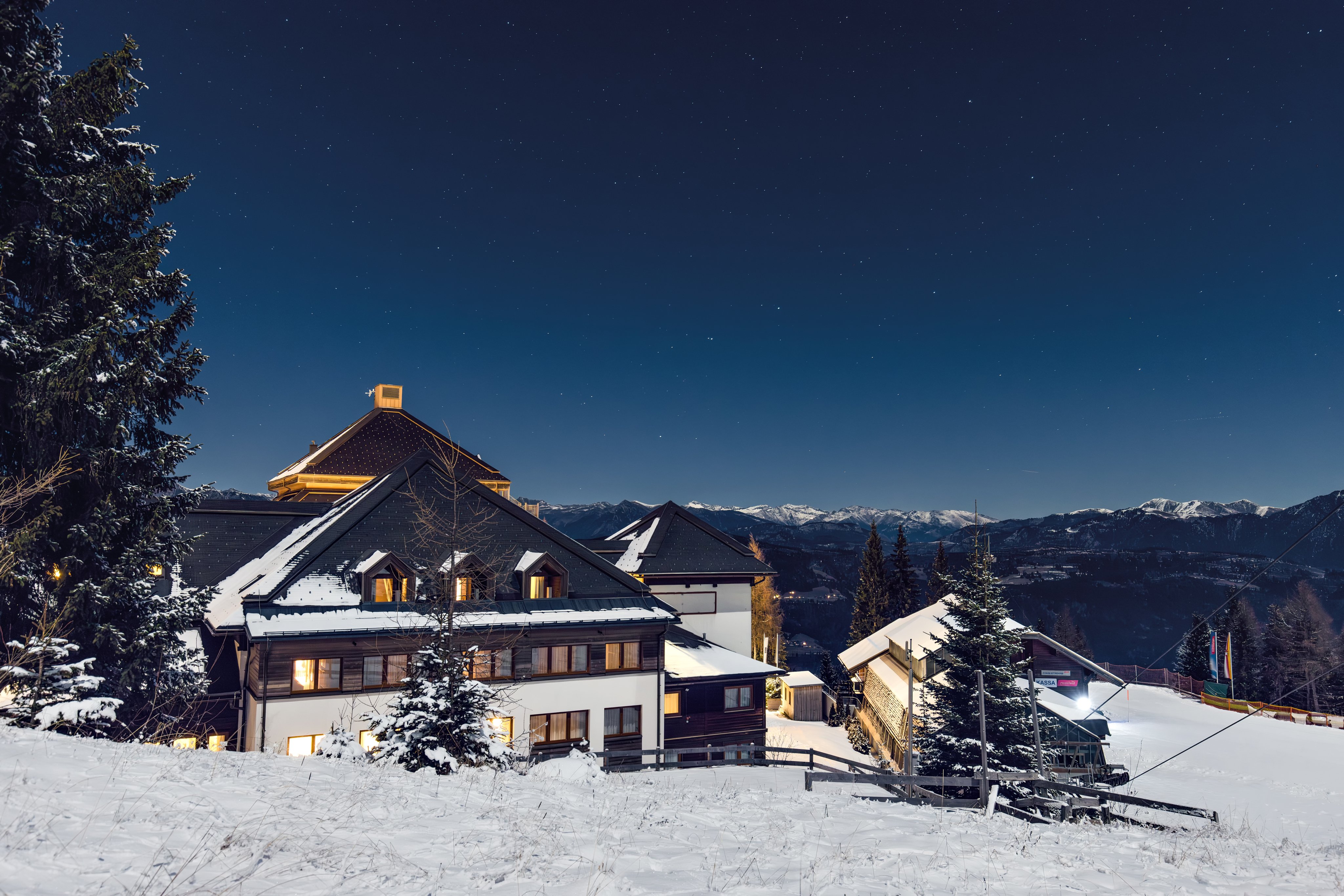 Helles Clubhotel im alpinen Winter mit Schnee und Himmel bei Nacht für barrierefreie Nutzung