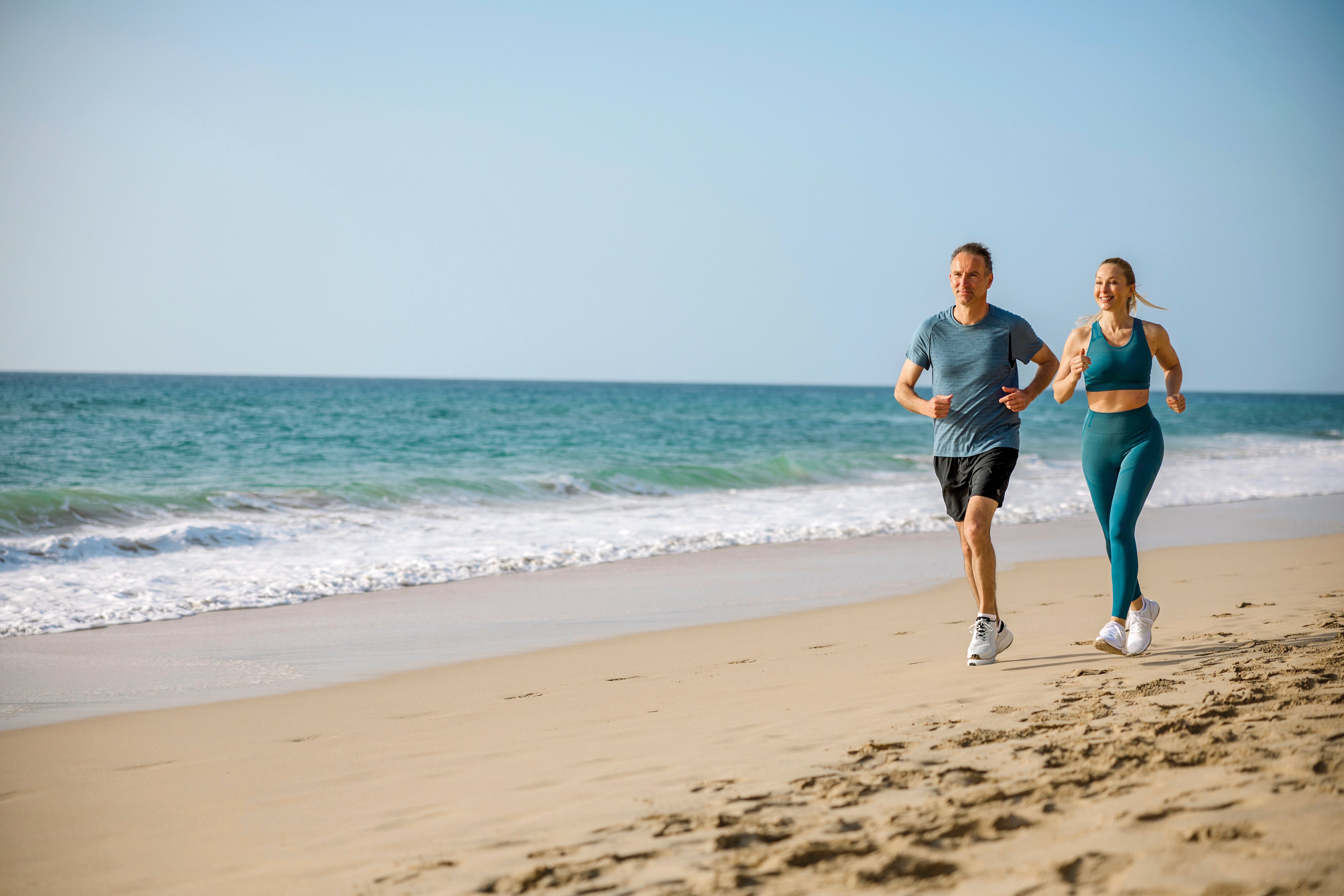 Zwei Personen joggen am Strand in einem Premium Cluburlaub von Aldiana