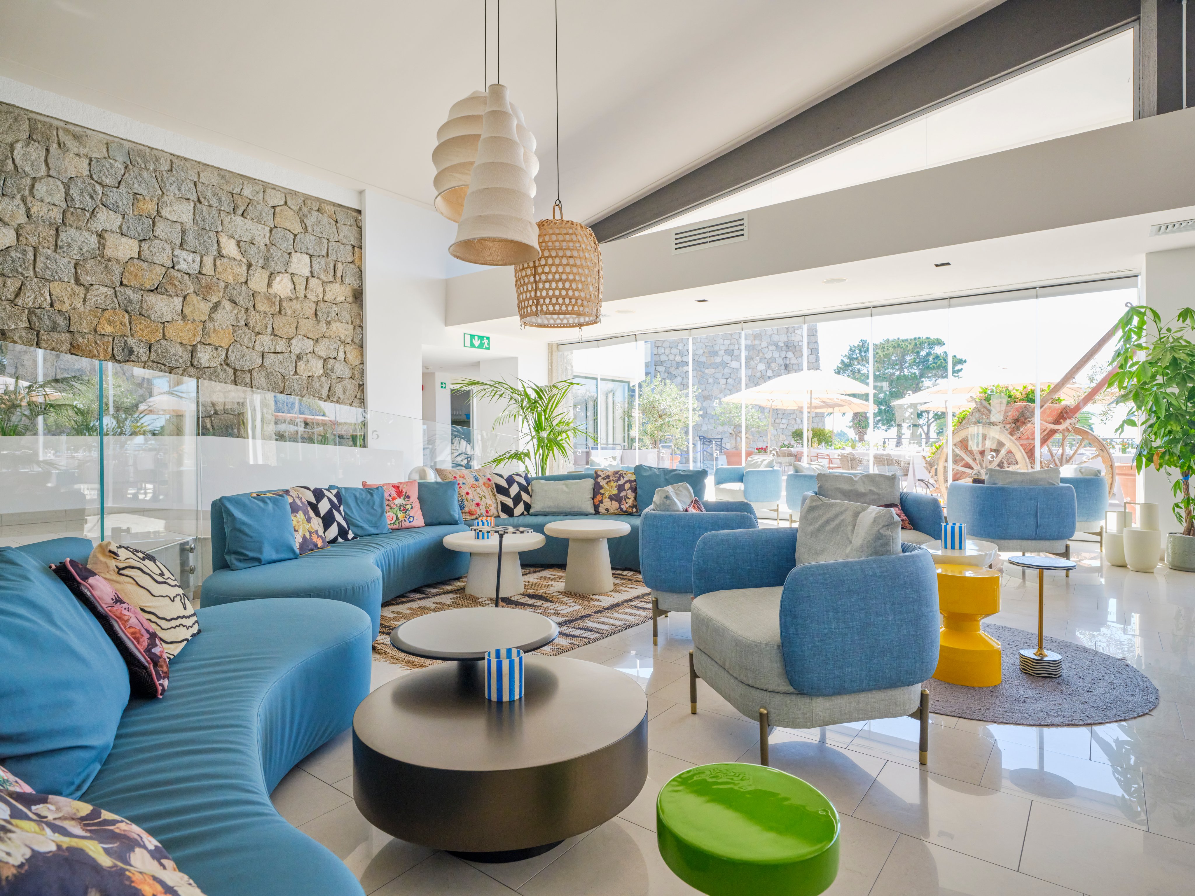 Moderne Lounge mit blauen Sitzgruppen, dekorativen Lampen und großen Fenstern für Premium Cluburlaub