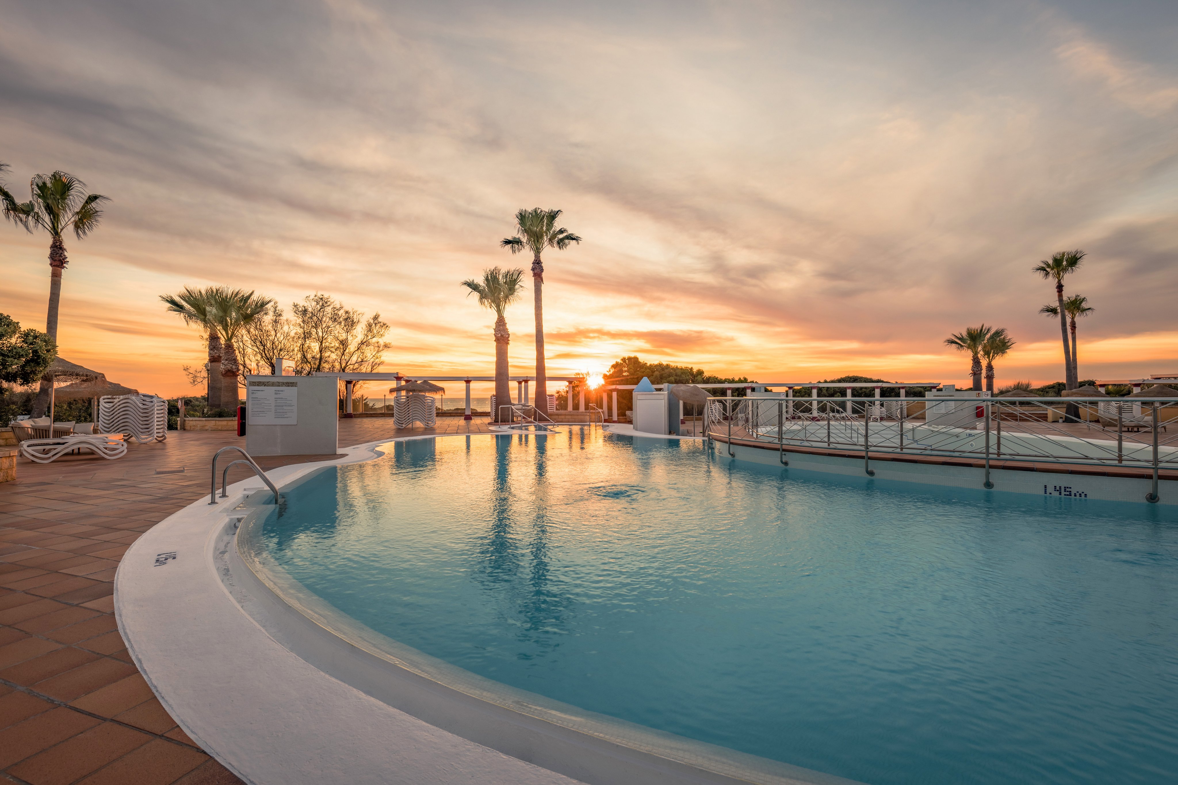 Schwimmbad im Sonnenuntergang bei Aldiana mit Palmen und relaxing Atmosphäre