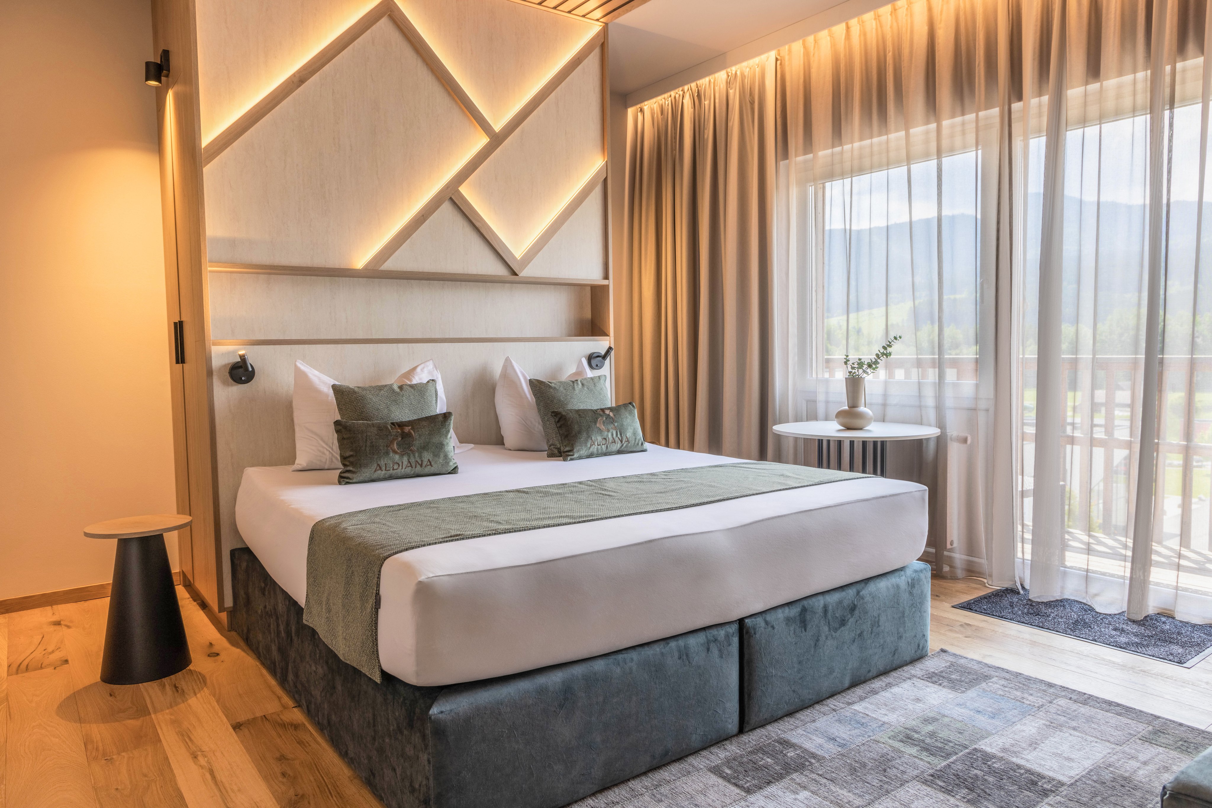 Elegant hotelzimmer mit Bett, Vorhängen, Pflanzen und Blick auf die Berge.