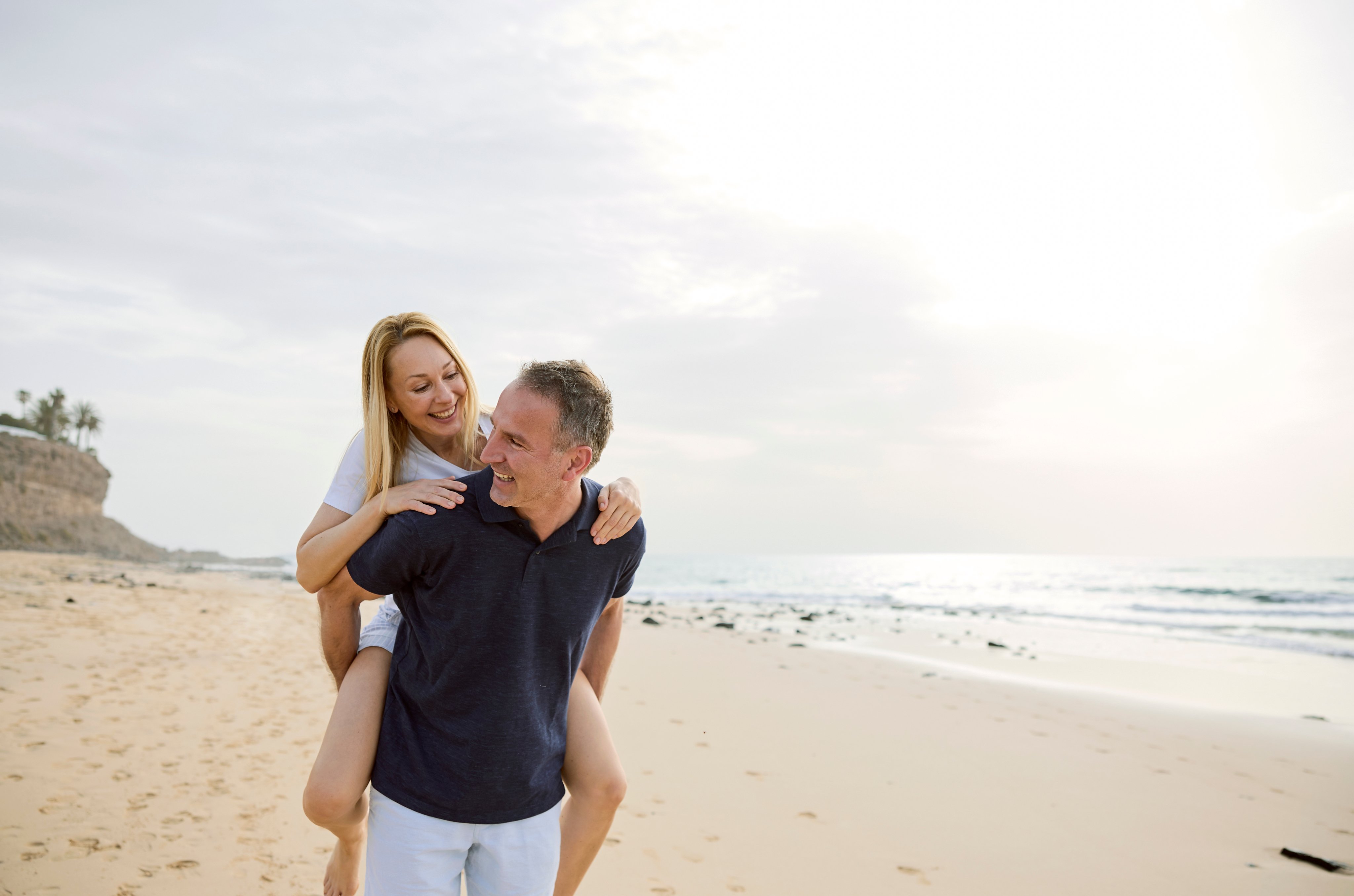 Zwei Erwachsene auf einem Sandstrand bei Sonnenuntergang, entspannt und glücklich.