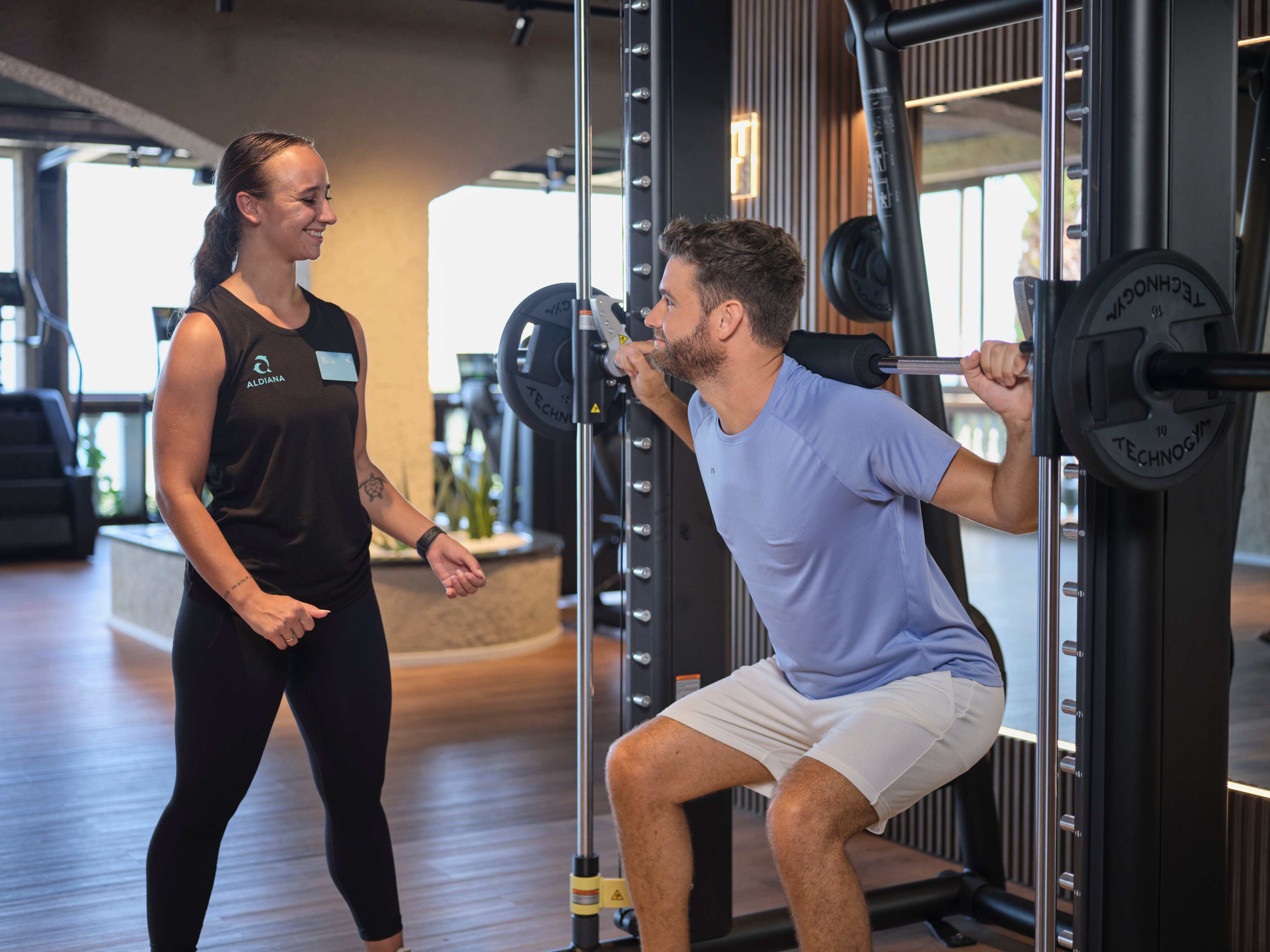 Personen im Fitnessstudio bei Krafttraining, moderne Ausstattung, entspannte Atmosphäre