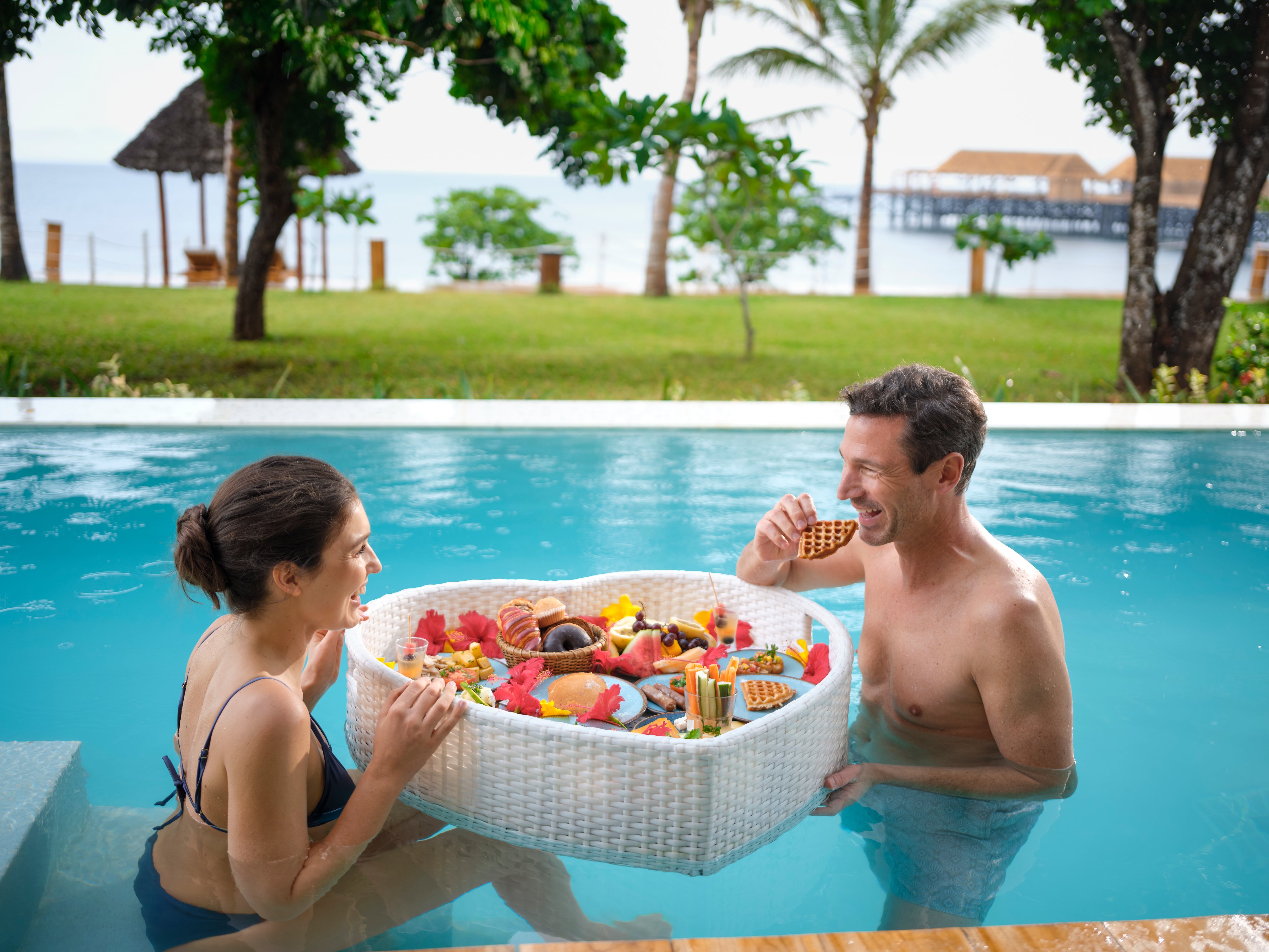 Ein Paar im Pool mit einer großen Badtasche voller Spielzeug und Schwimmreifen auf Premium Cluburlaub bei Aldiana