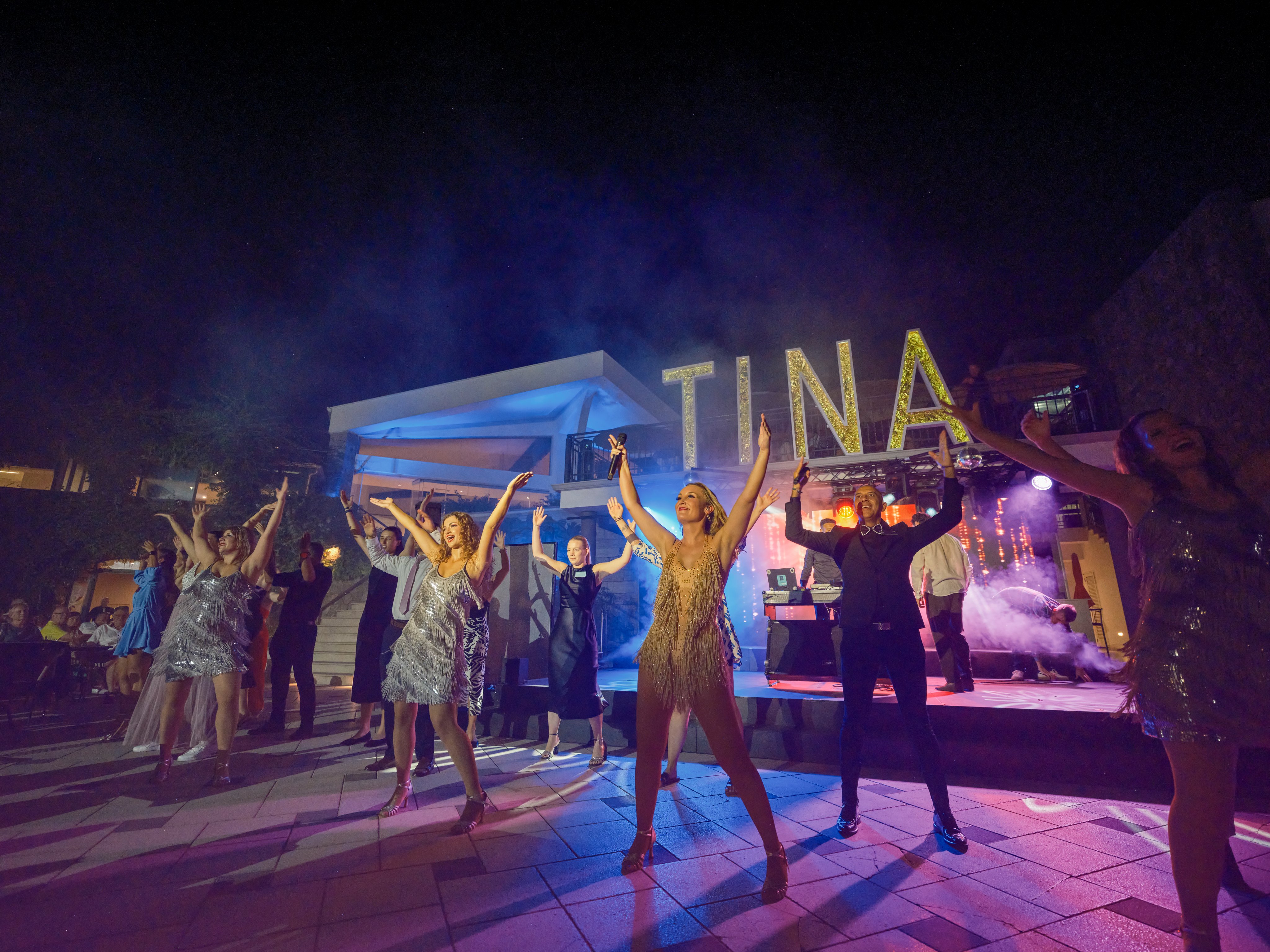 Tanzende Gäste bei Abendveranstaltung im Aldiana Premium Cluburlaub, farbige Lichter.