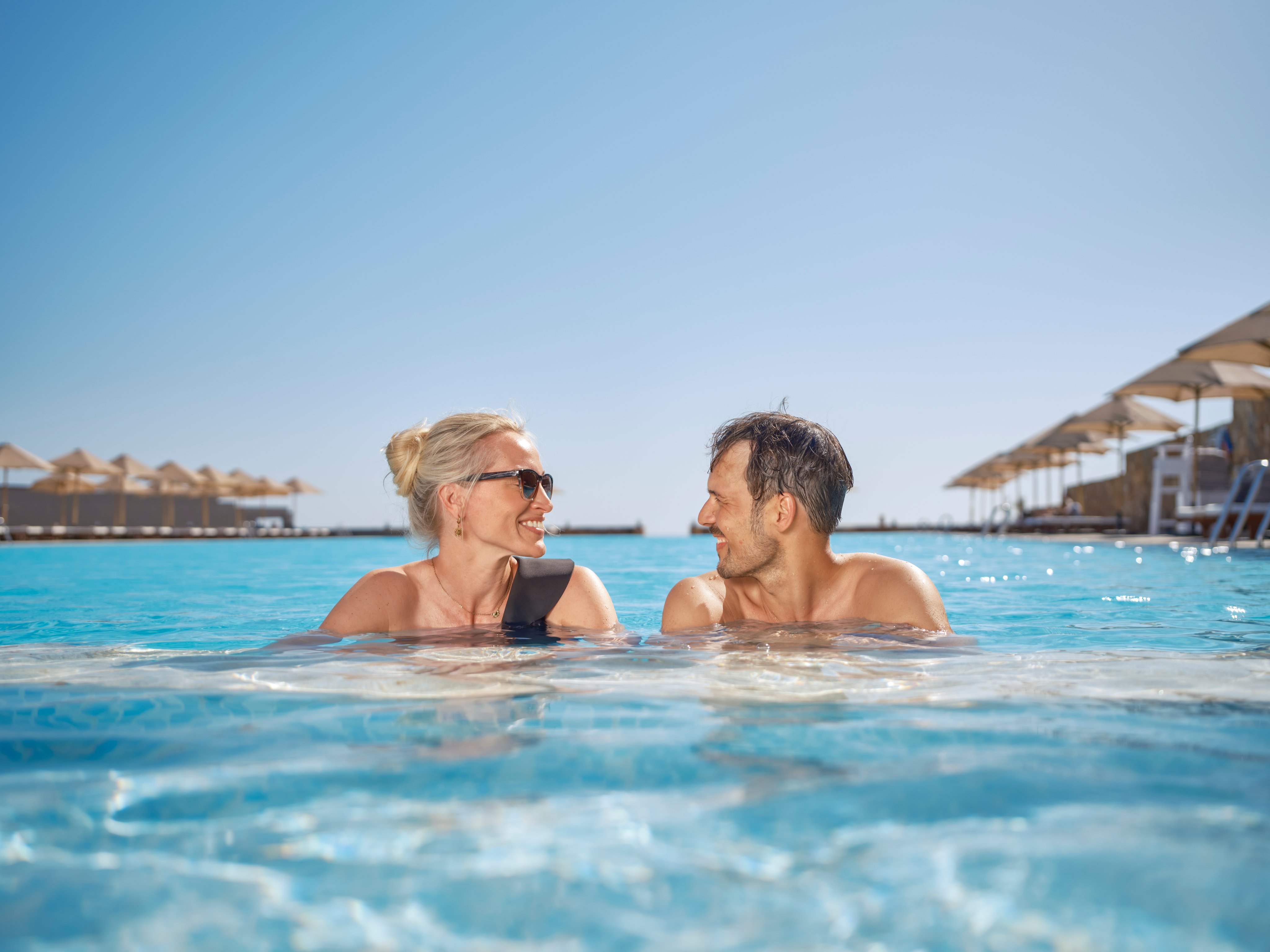 Zwei Menschen entspannen im Pool an einem sonnigen Tag bei Aldiana Urlaub