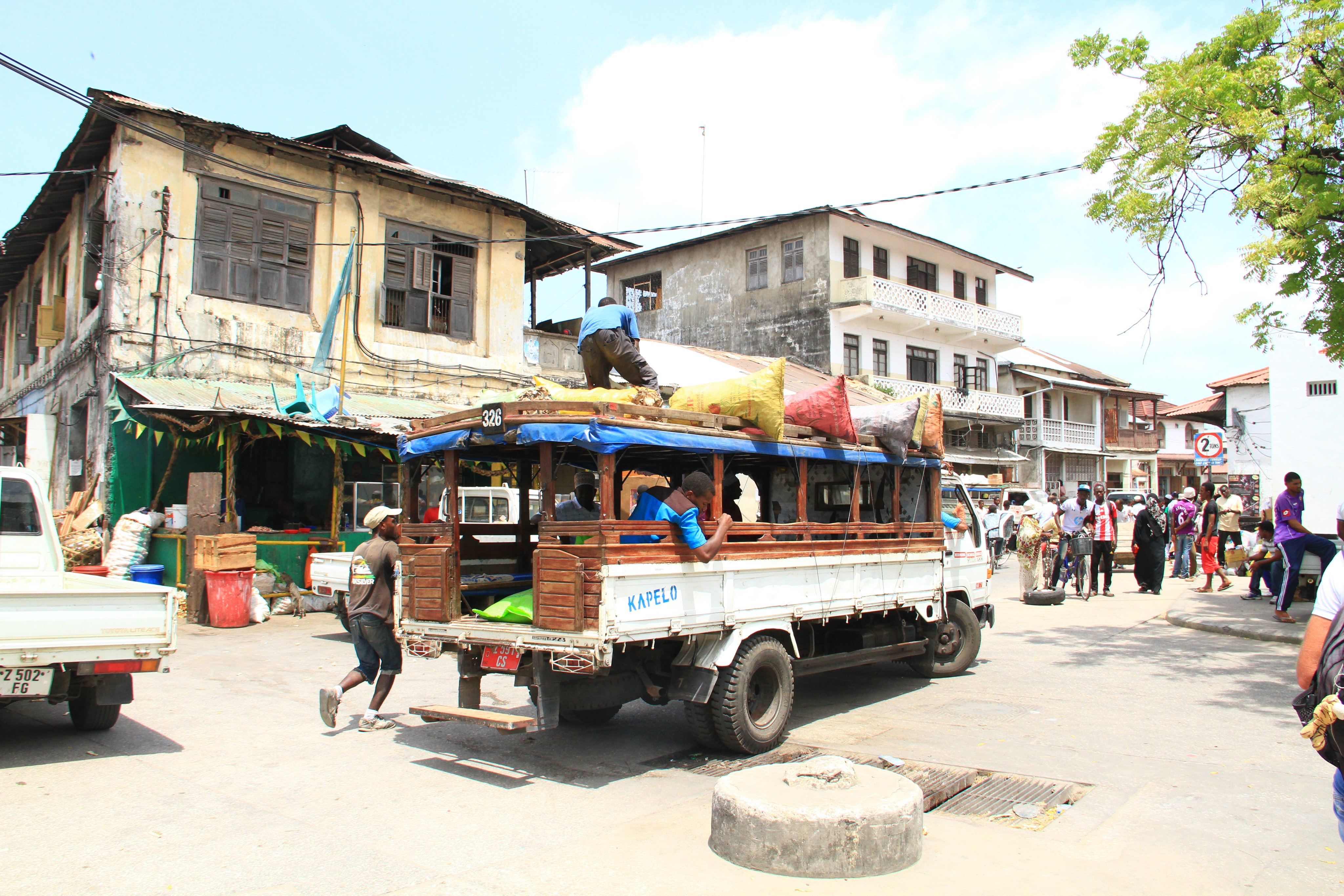 Ein verkehrsreicher Markt mit einem offenen Transporter und alten Gebäuden im Hintergrund