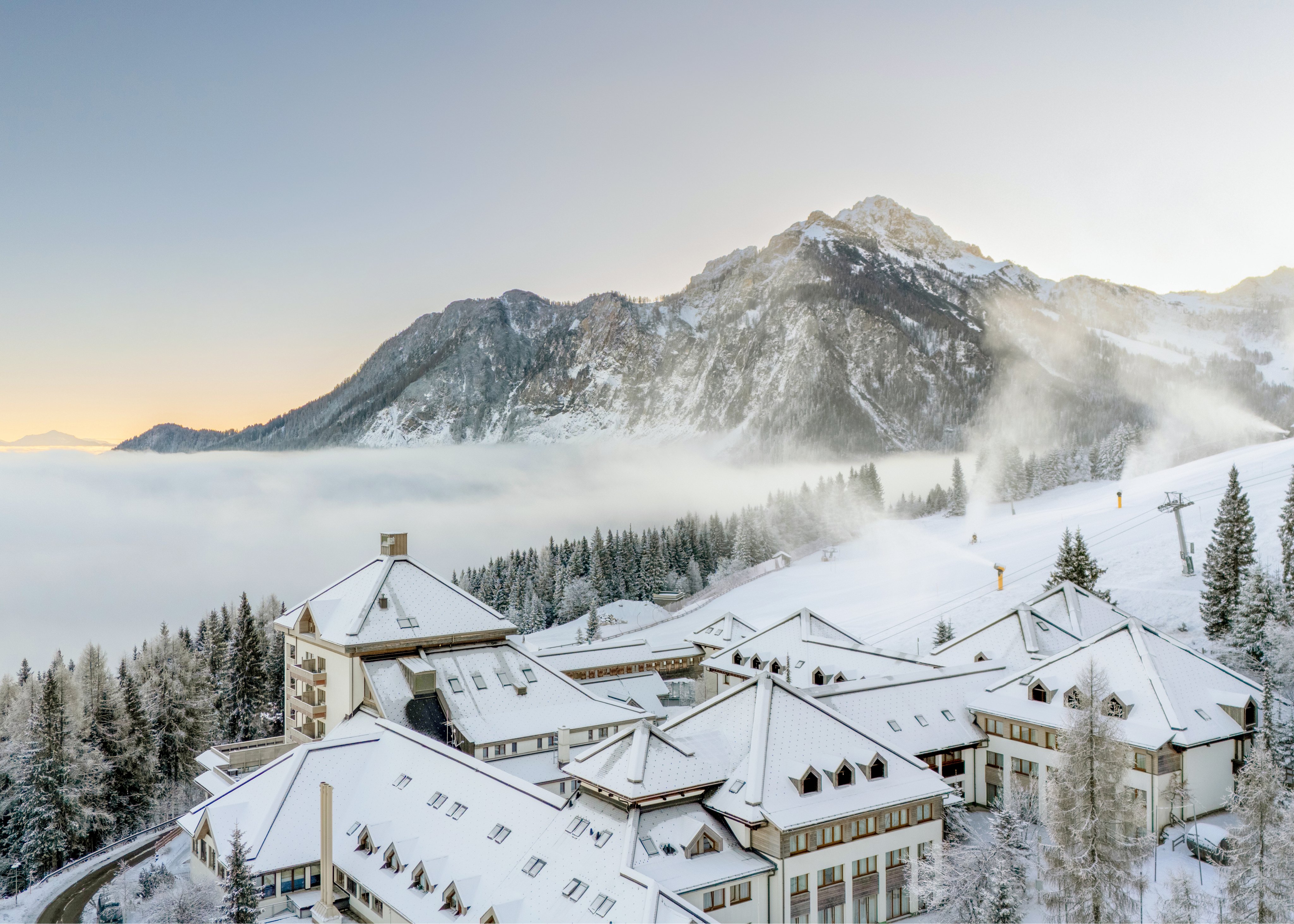 Winterlandschaft mit verschneiten Hotels und Bergen im Hintergrund, ruhige Urlaubsatmosphäre