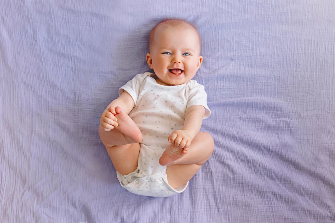 Baby liegend auf lila Bettdecke, entspannter Moment in einem Premium Cluburlaub bei Aldiana