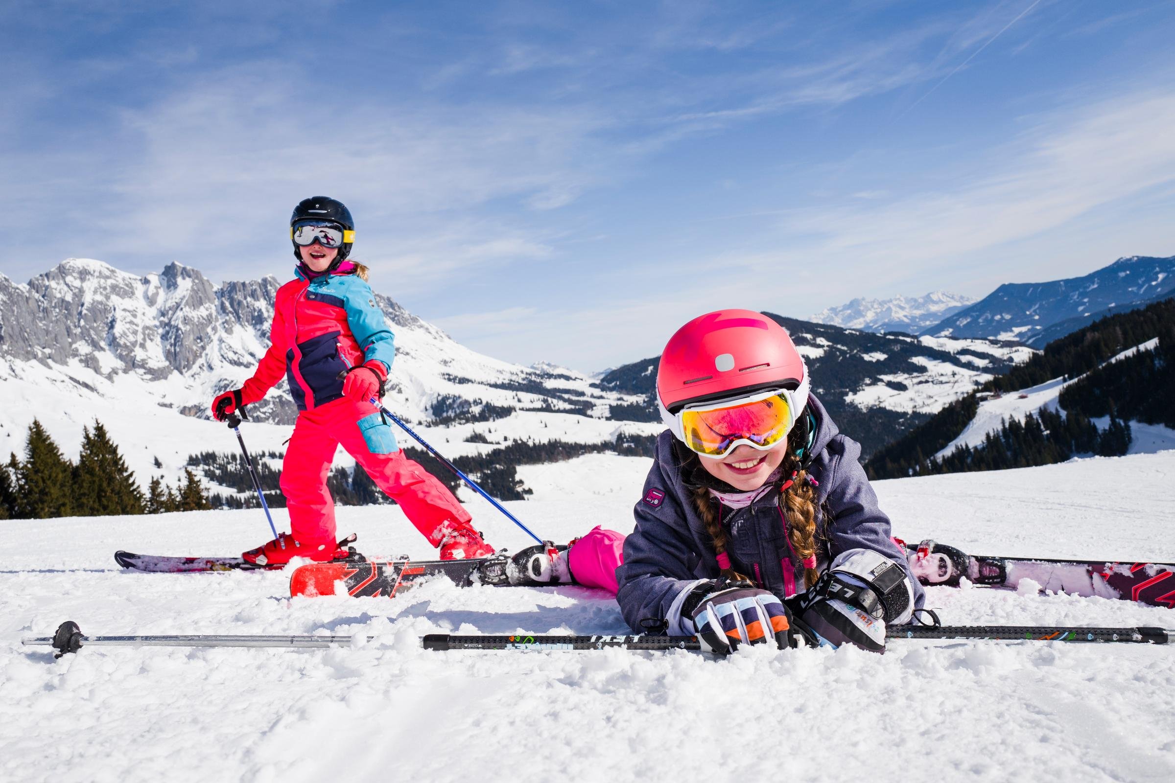 Zwei Kinder beim Skifahren im Schnee in einer malerischen Berglandschaft, sonniger Tag
