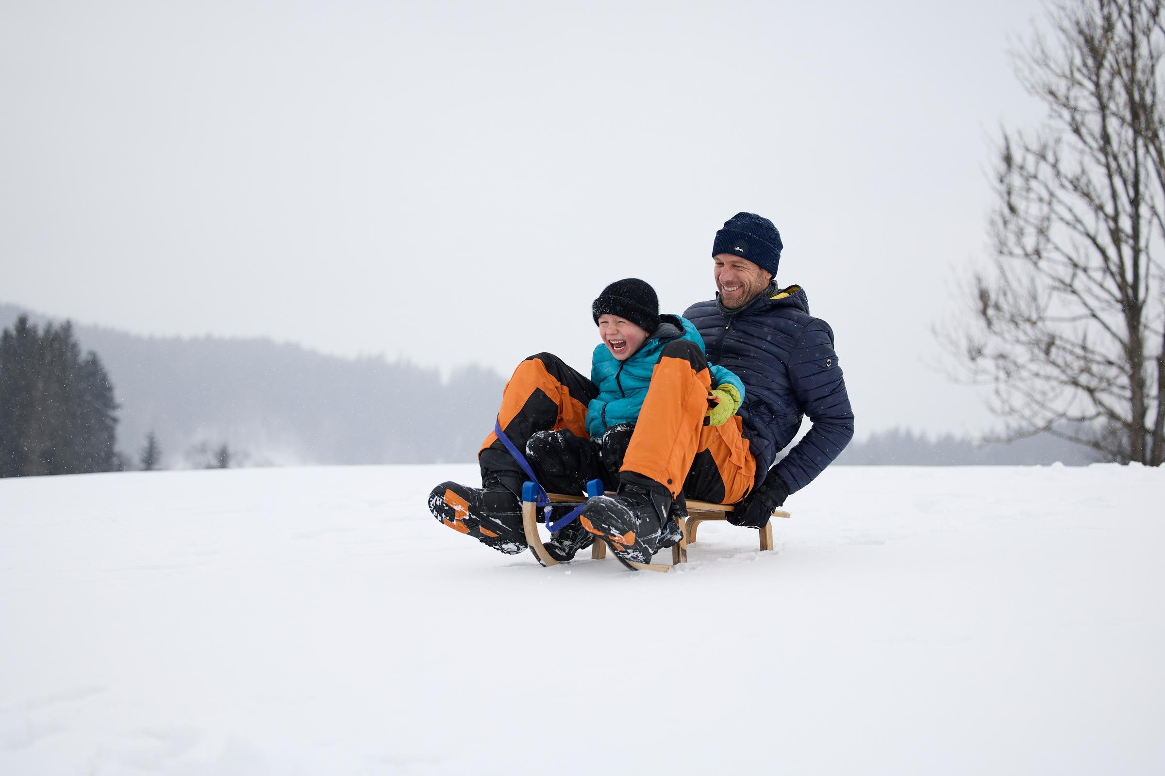 Zwei Kinder beim Rodeln im Schnee, fröhliche Wintersportaktivität bei Aldiana Urlaubsangebot